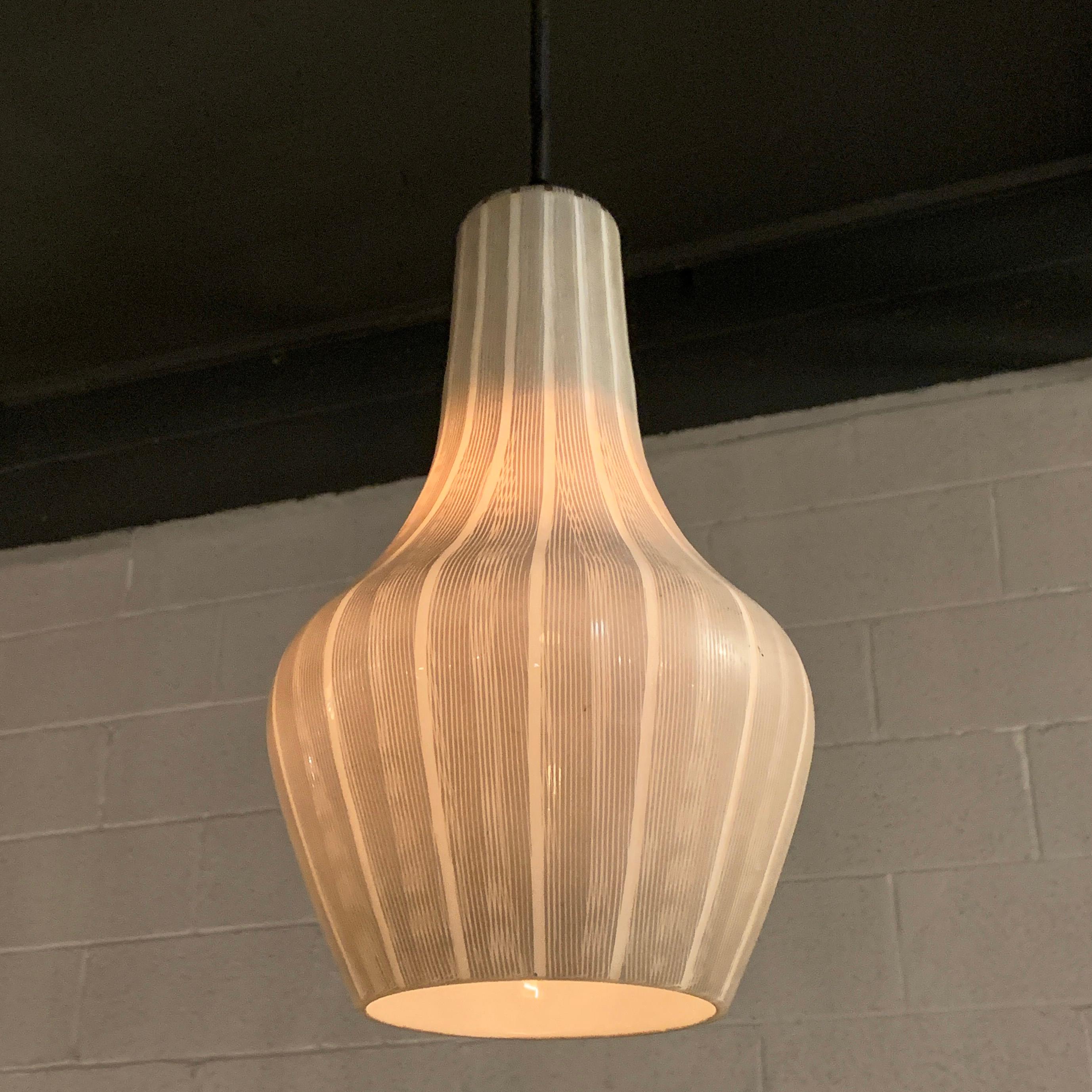 Scandinavian Modern, art glass pendant light features a finely striped black and white exterior and shapely form. The pendant is newly wired with 60 inches of cloth cord to accept up to a 100 watt, medium socket bulb. Marked Made In Sweden.