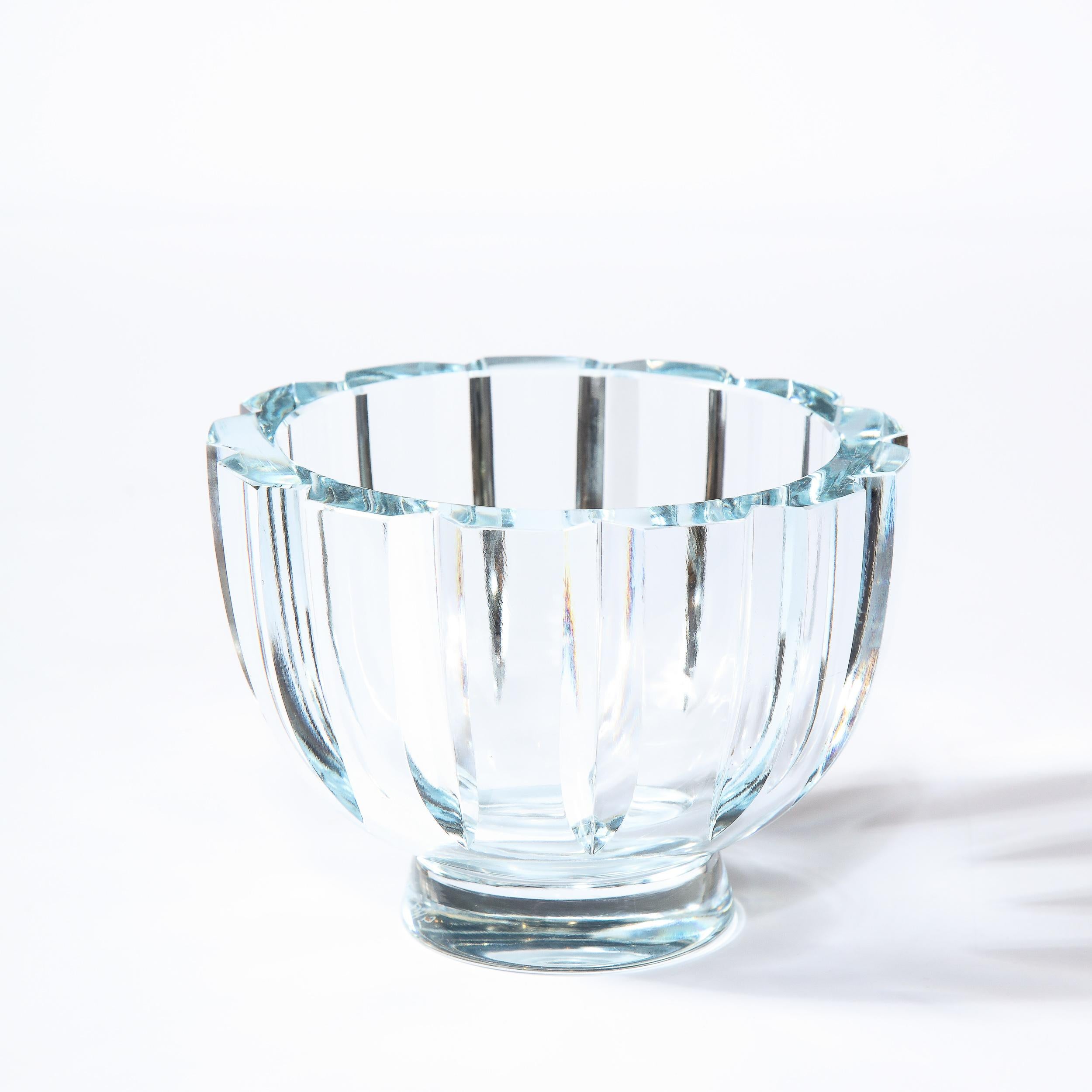 This stunning Mid-Century Modern bowl was realized in Sweden circa 1950. It features a cylindrical form that tapers to its circular base with deep triangular notched channel faceting running along the perimeter- all in a subtle light blue hue. With