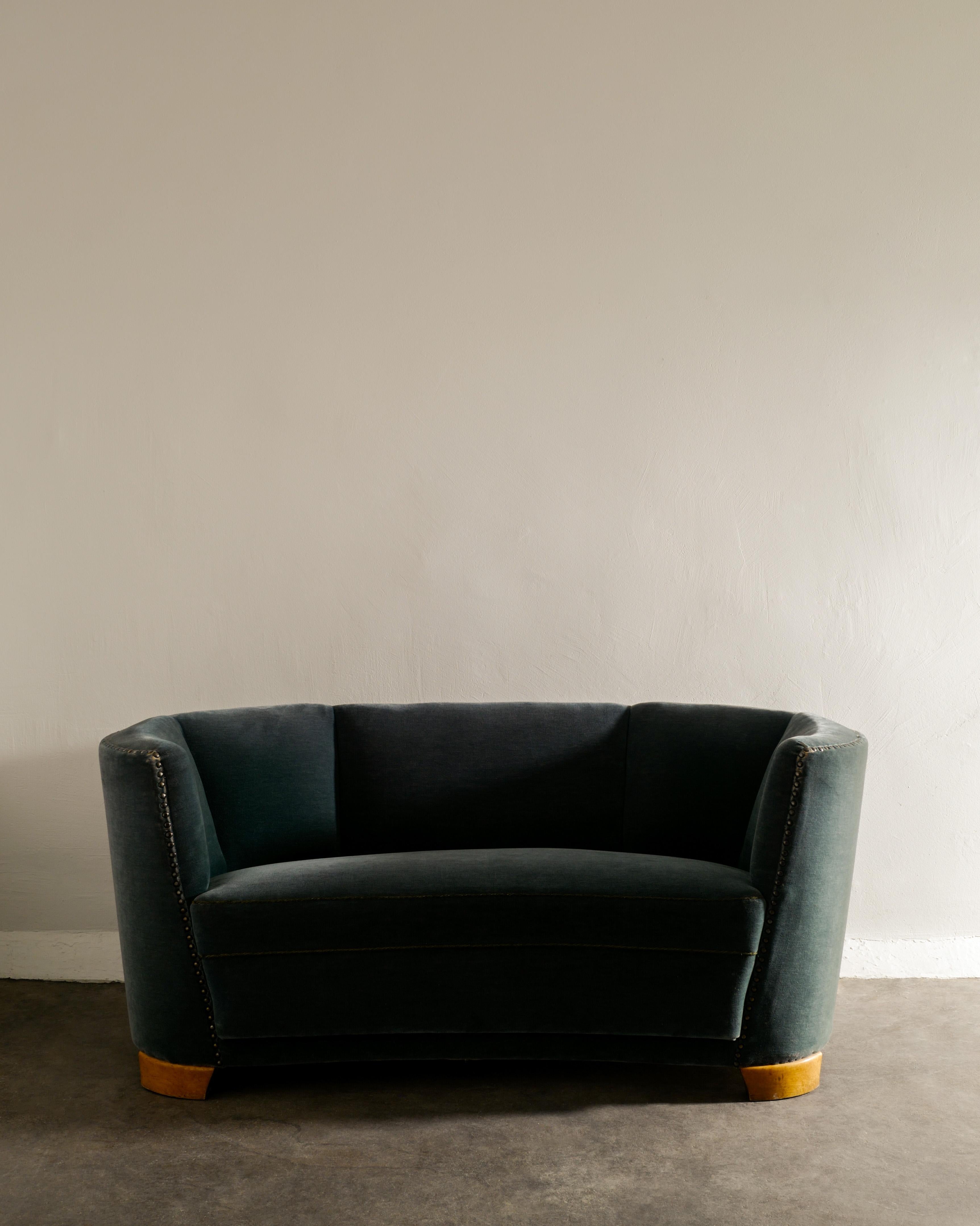 Rare two seater Swedish mid century modern curved sofa in style of Otto Schultz. The dark green velvet upholstery appear to be original and is in good condition. Many nice details such as the feet in beech and iron rivets along the top edge.