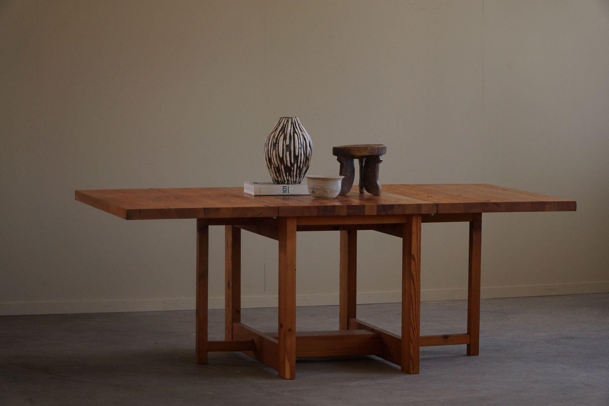 This Swedish mid-century modern drop-leaf folding table is made from solid pine and features a warm, rich patina that highlights its natural wood grain. Crafted in the 1960s and Designed by Sven Larsson.
The table's design is both functional and