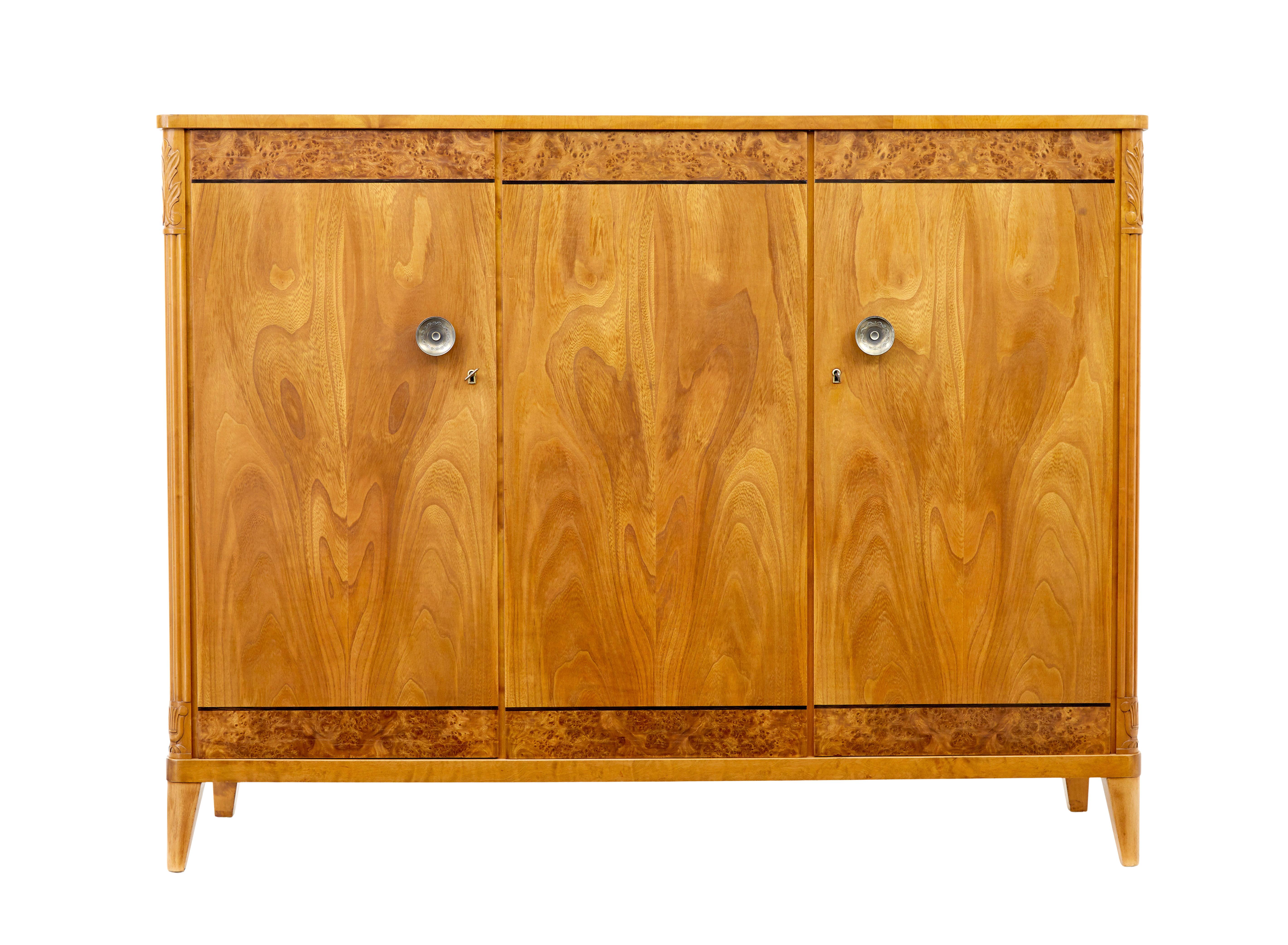 Swedish mid century modern elm and birch sideboard circa 1950.

Classic styling on this elegant sideboard, using elm, birch and burr veneers. Front 3 doors veneered in matched elm, burr decoration to top and bottom with stringing, each with ornate