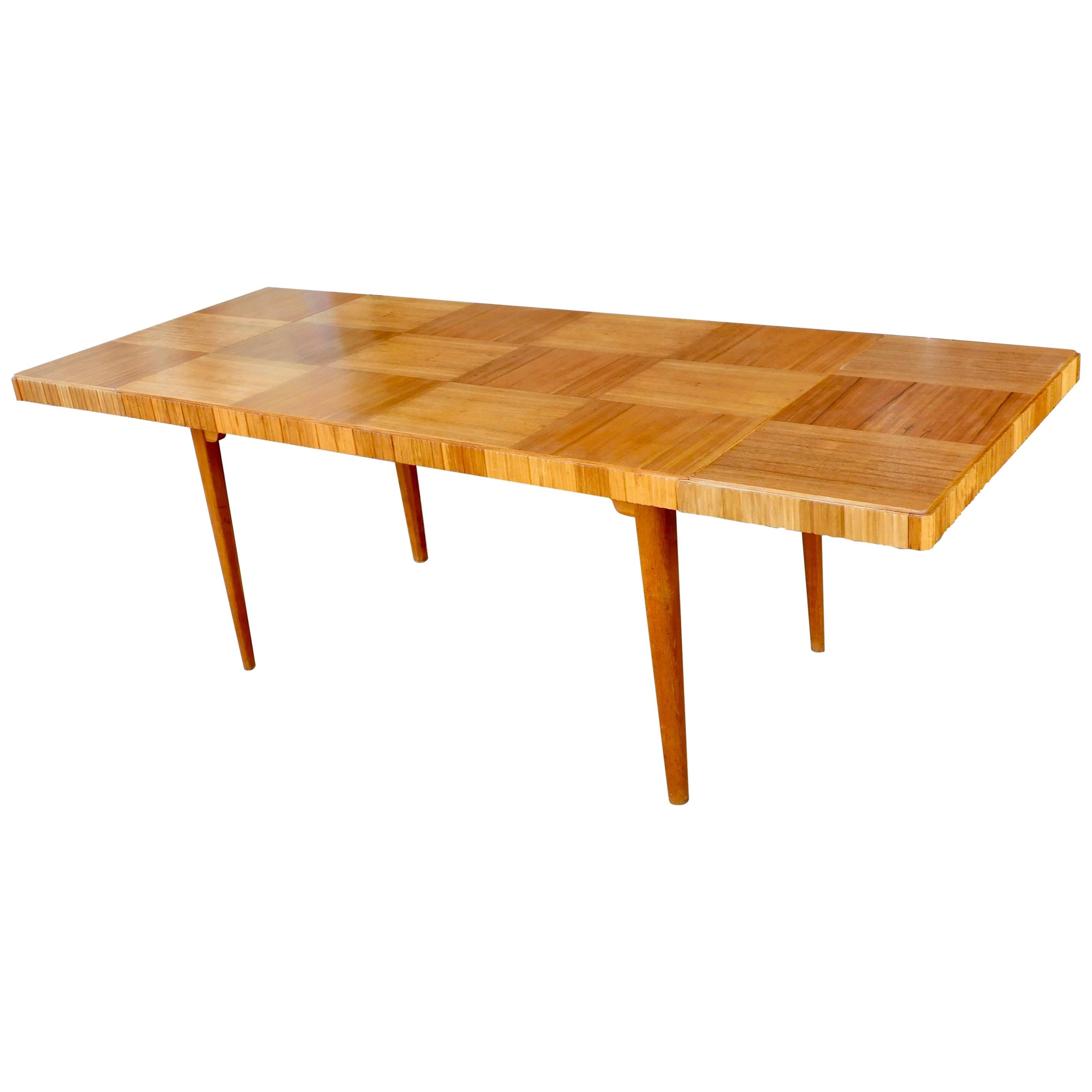 Exceptional Swedish Mid-Century Modern extendable dining table.
Base rendered in birch wood. Parquetry top in highly figured natural mahogany.
This table can function either as a four-seat or as an eight-seat with the additional of two side