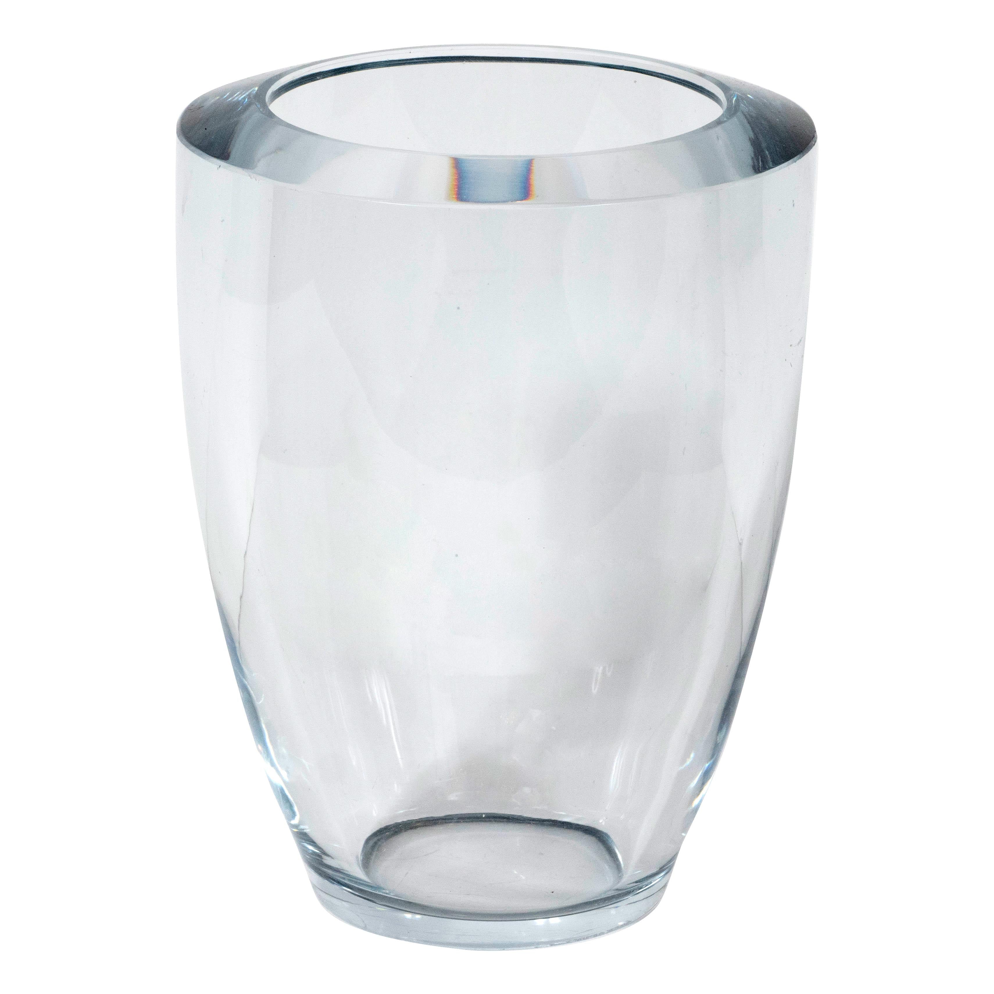 This elegant Mid-Century Modern vase was realized in Sweden circa 1960. It features a curved cylindrical volumetric body with a circular mouth in thick translucent pale blue hand blown glass. With its clean lines and beautiful glass quality, this