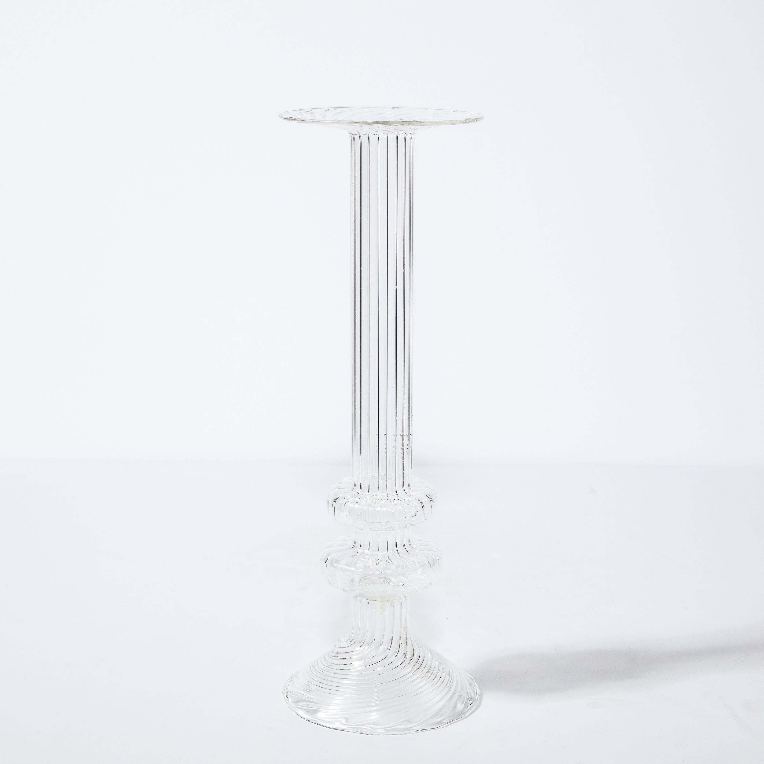 This elegant Mid-Century Modern candleholder was realized in Sweden, circa 1960. It features a cylindrical body with two sculptural volumetric circular details approaching its base; a circular canvilevered mouth and conical all in translucent