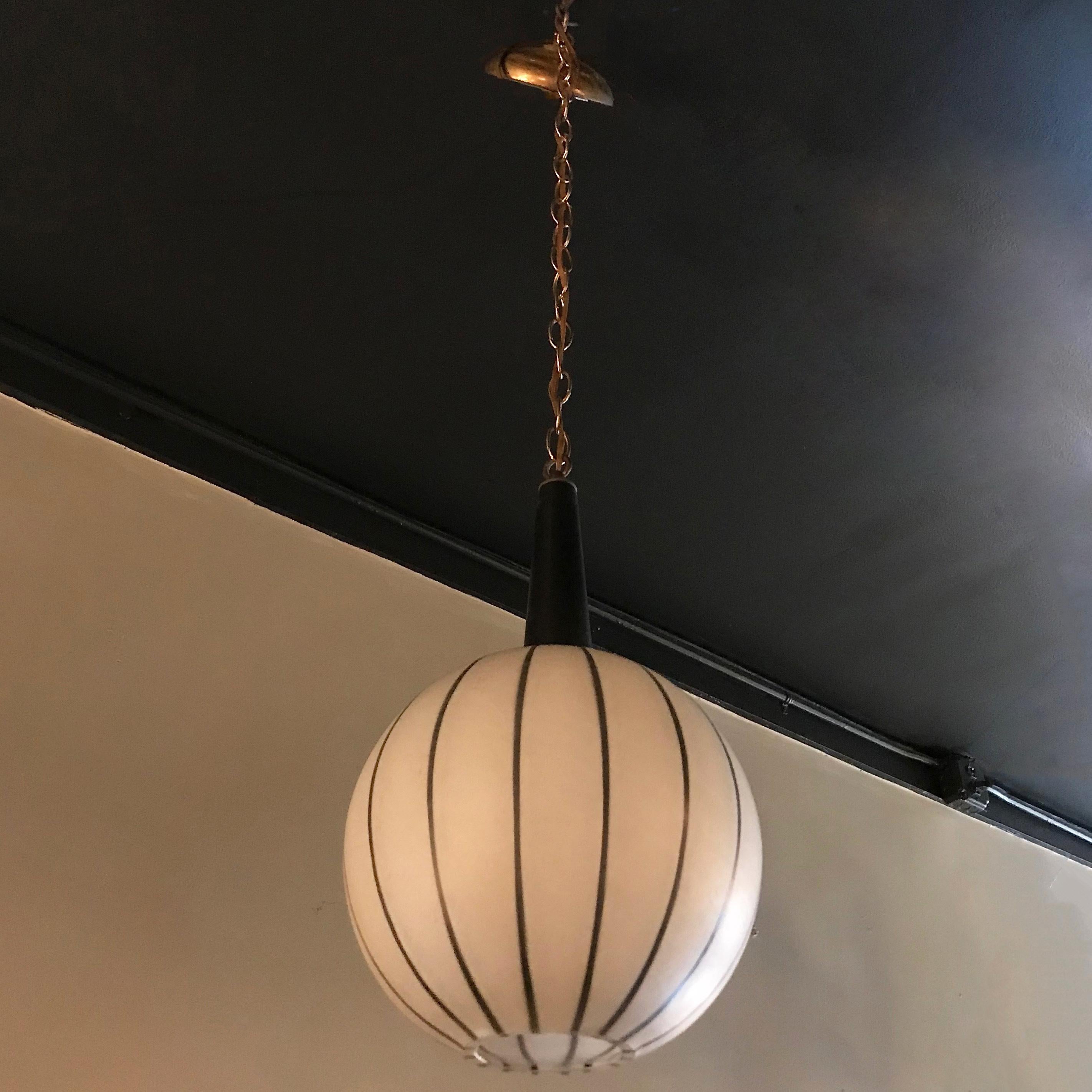 Swedish, Mid-Century Modern, pendant light features a graphic, black and white striped, crackle textured glass, open globe shade with black stem on 24 inches of brass chain with matching canopy. The pendant's overall height is 42 inches and is newly