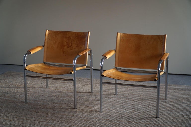 A pair lounge chairs in nicely patinated leather and tubular chromed steel frame. Designed by Tord Björklund, model Klinte in 1970s. 

A great object for the modern interior. A warm colour and patina that pair well with the Minimalist scandinavian