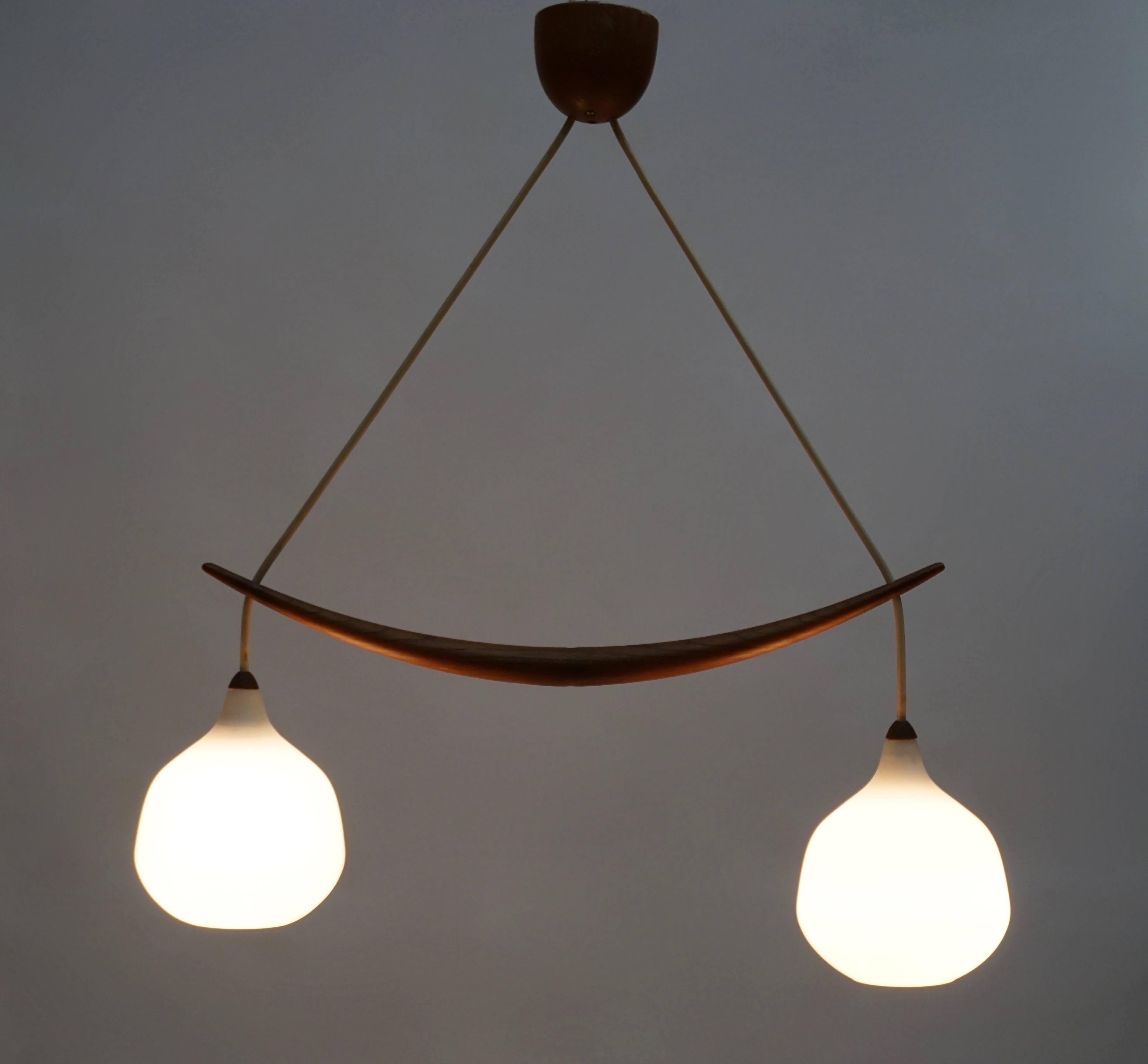 Pendant in oak and opaline glass. The lamp features two hanging glass spheres, divided by a carefully carved oak stick.
Measures: Height 65 cm.
Width 75 cm.