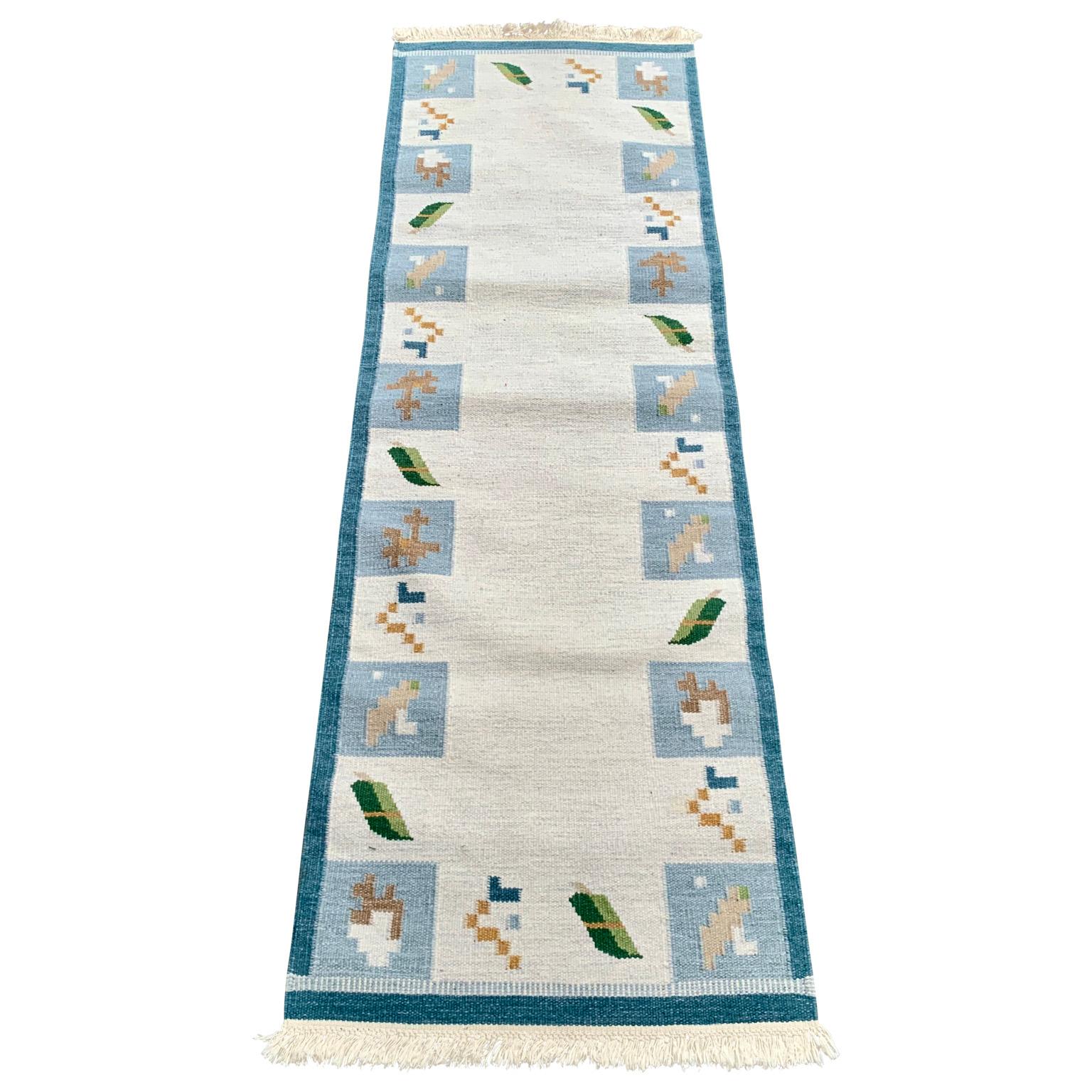 A Mid-Century Modern vintage handmade Swedish carpet in wool featuring a geometric pattern around the border in blue tones. This Scandinavian rug is more unusual because it is a runner and not a typical classic rectangular carpet. The tradition of