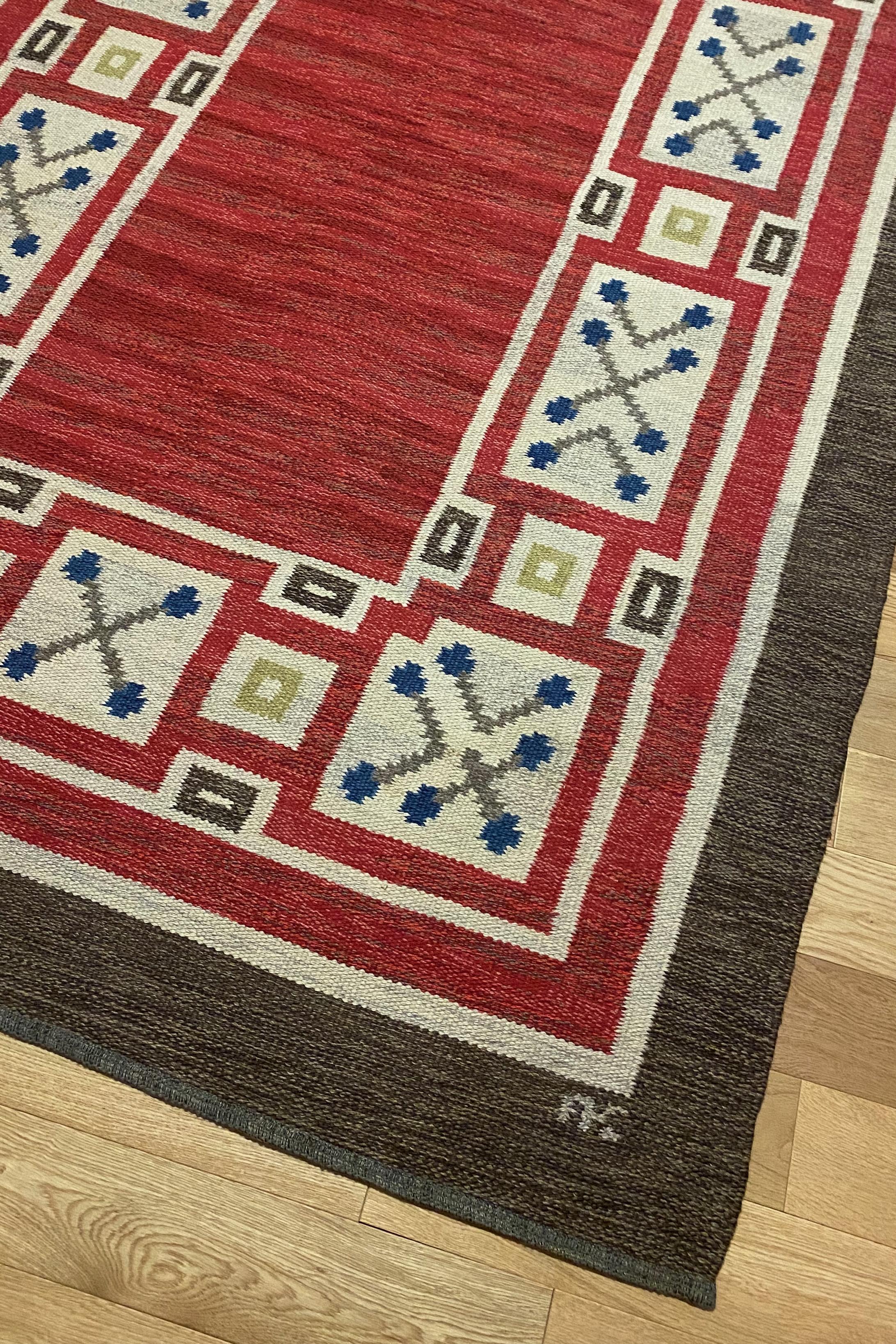 Stunning Mid-Century rug by Aina Kånge with a red and brown base and blue, yellow and sand accent colors. As usual in Aina Kånge designs the pattern is classic and timeless. Her initials are visible at the lower right side. Very good condition with