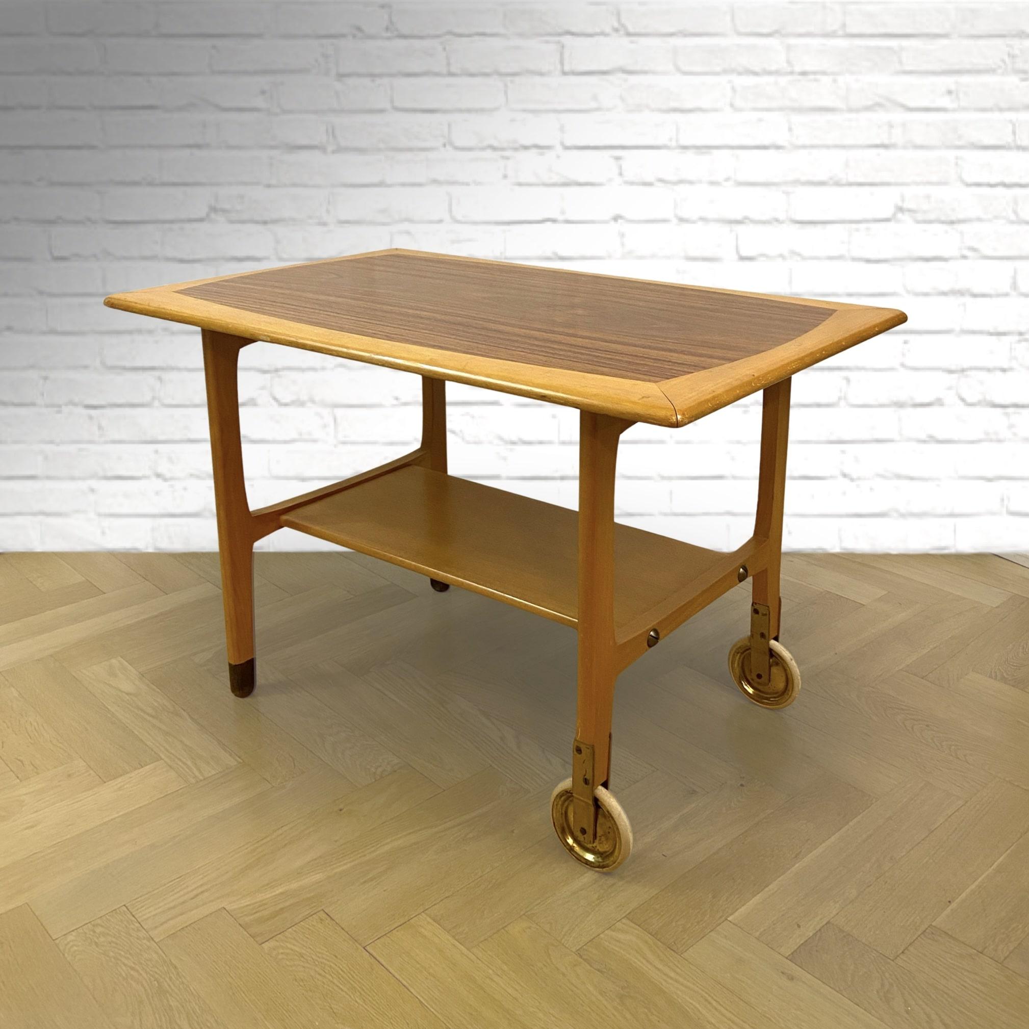 A Swedish mid-century serving table, made from beech wood and walnut. Two legs on casters, the other two with dark wooden feet. The shelf gives the table extra space for storage.