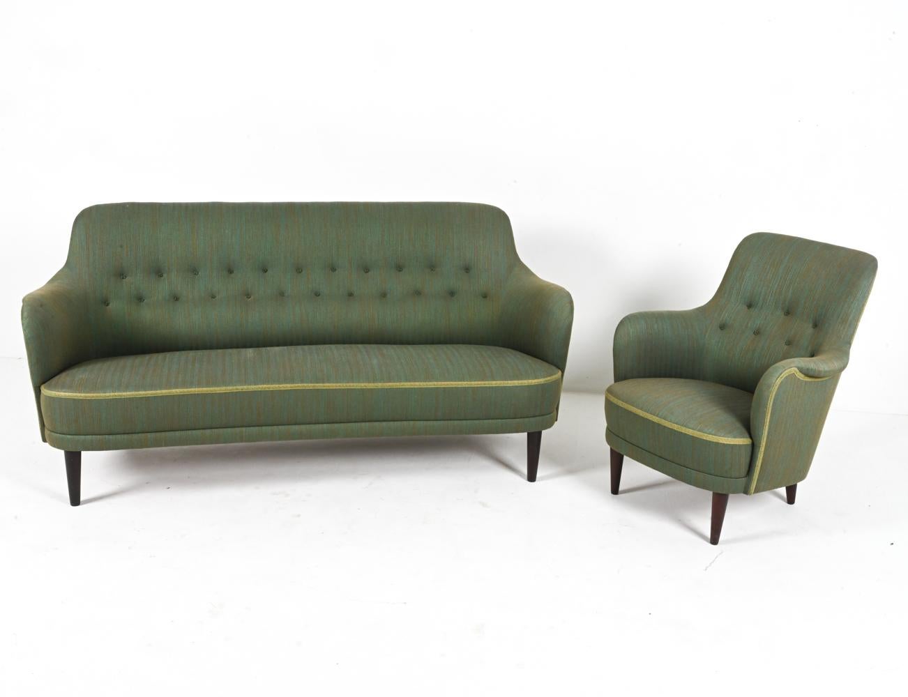 A classic Mid-Century living room set by the legendary Swedish furniture designer Carl Malmsten, featuring mahogany-stained beech wood legs and green twill upholstery. 

NOTE: Dimensions provided refer to the sofa. The chair measures H 33.5