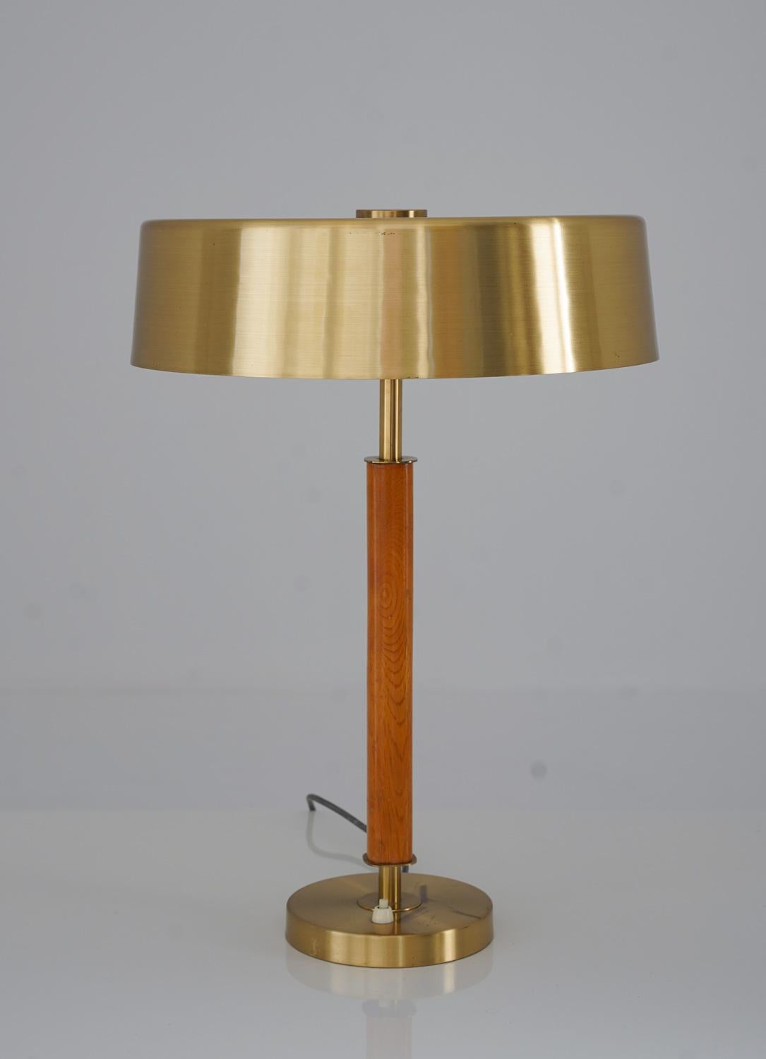 La lampe de table Boréns est une pièce étonnante du design scandinave. La lampe présente une tige en laiton brossé, entourée d'un abat-jour et reposant sur un pied dans le même matériau. La combinaison du laiton et du chêne crée une atmosphère