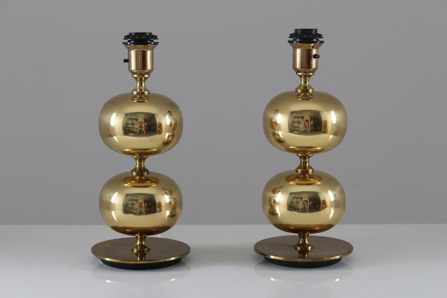 Two stunning midcentury table lamps by Stilarmatur Tranås, Sweden.
With a heavy bottom plate and two large brass spheres, these lamps give an exclusive impression.
The lamps seem to be produced in different years, as the underside of the foot