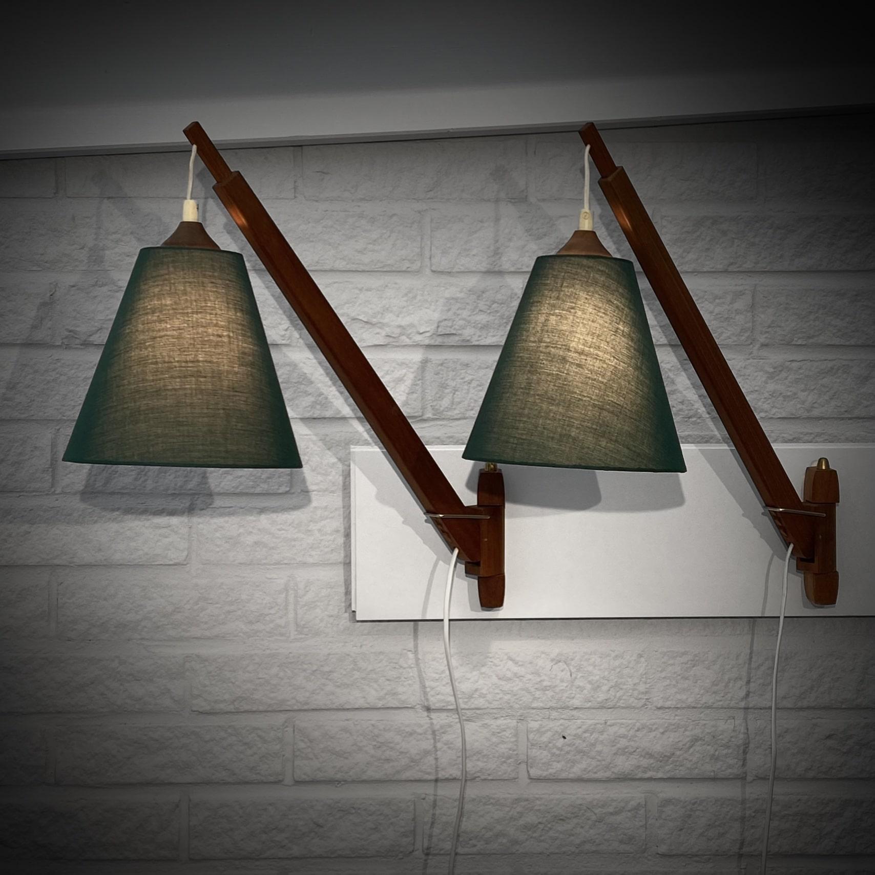 A pair of Swedish modernist wall lamps made from solid teak with pivotal telescope arm adjustable in height. A model known as fishing rod lamps. Brass details and cone shaped shades upholstered in green textile. Produced by an unidentified Swedish