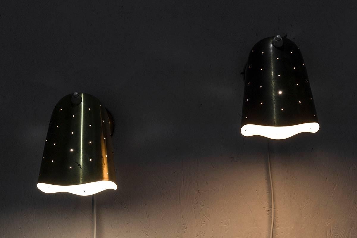 Swedish Mid-Century Modern wall lights or bed lights in perforated brass by Swedish manufacturer Boréns. The lamps give a cozy, ambient light when lit. 
Condition: Beautiful original patina on the brass.
 