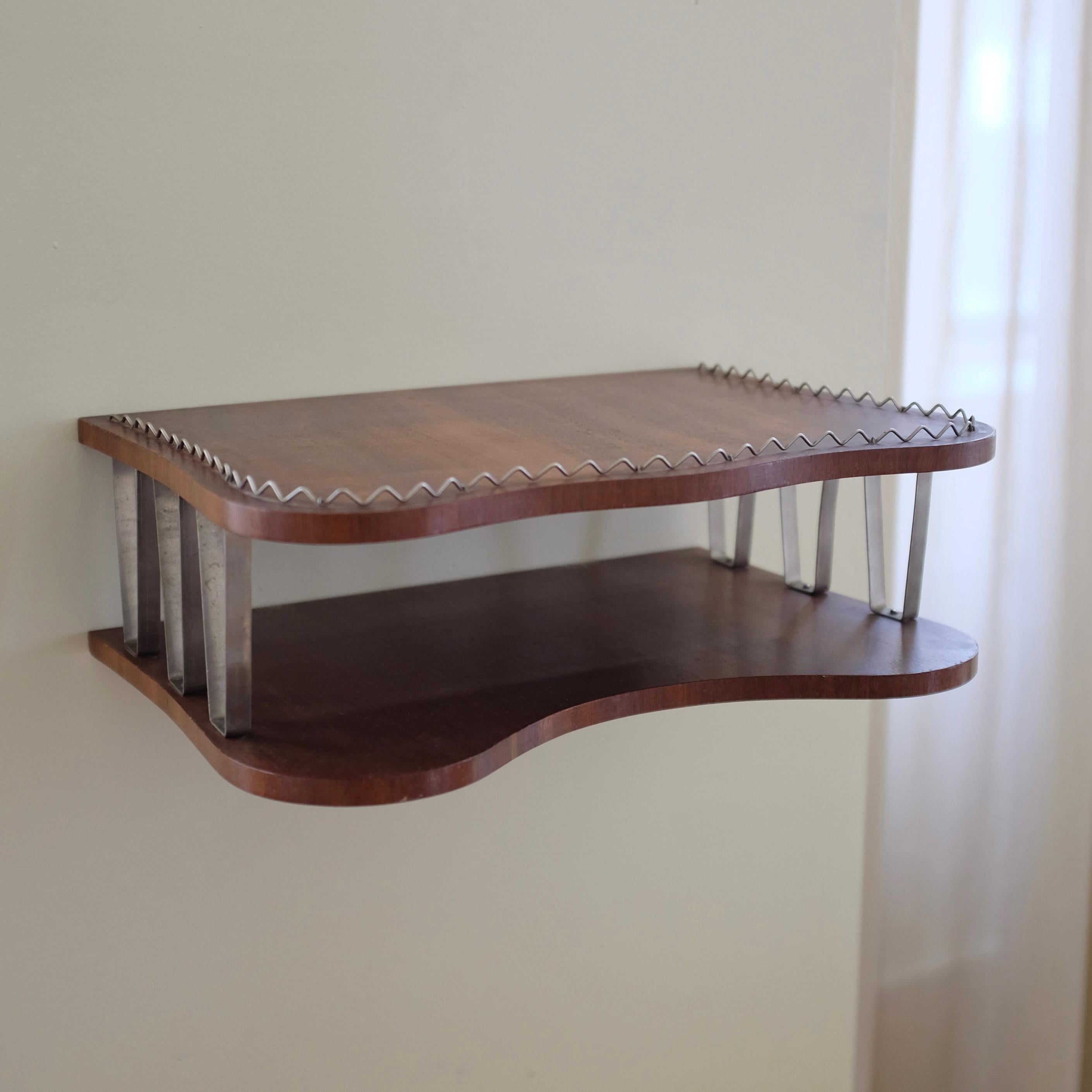 Preciosa estantería sueca de pared de mediados de siglo, decorada con detalles de filigrana metálica alrededor del estante superior. Frontal curvado en forma de riñón que añade encanto con la posibilidad de utilizarlo para exponer objetos más