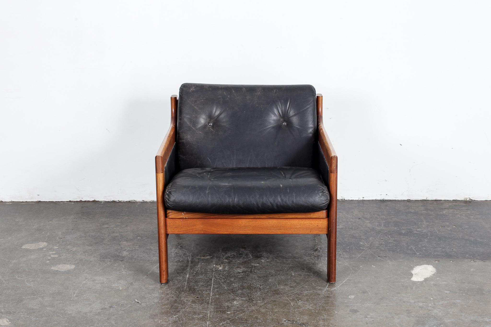 Swedish lounge chair in black leather designed by Karl Erik Ekselius, produced by JOC Möbler, this piece is supported by an angular wooden frame and leather panels on the sides. Leather shows wear and patina consistent with age but no tears or