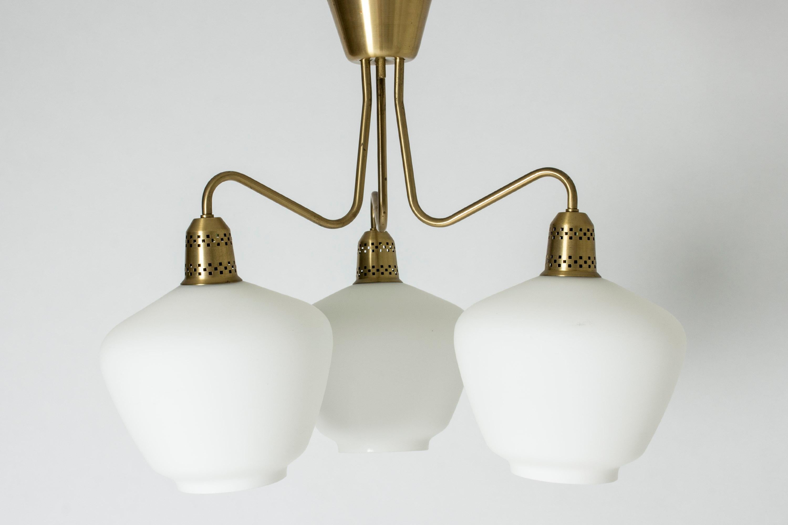 Elegant Swedish midcentury chandelier, with a brass frame and large, opaline glass shades. Beautifully cut out pattern in the brass light bulb holders.