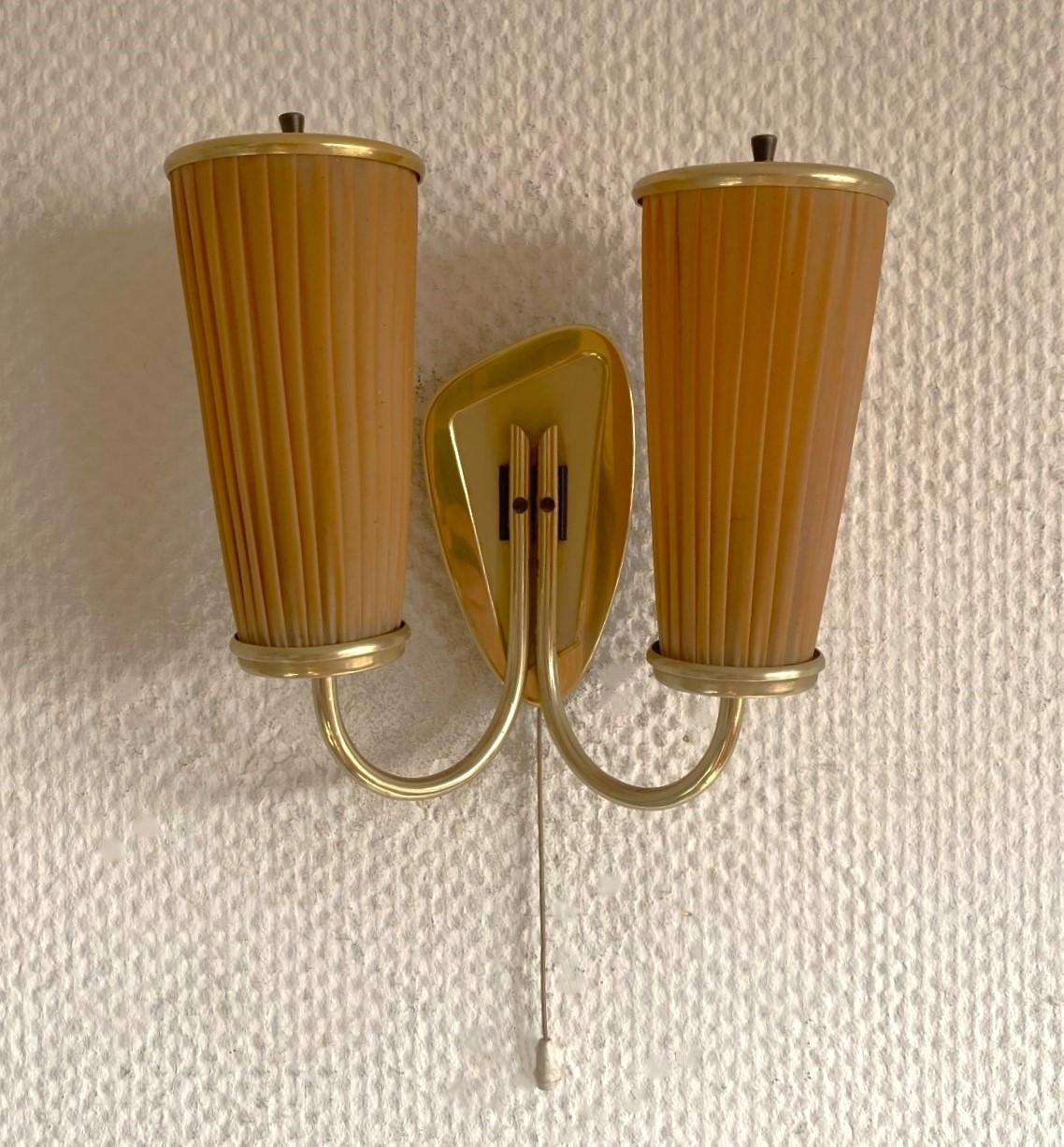A Lovely brass and fabric two-light wall sconce designed and produced in Sweden in the 1940s. Clean lines and organic design from the Scandinavian Modern period, two-arm with beautiful pleated fabric lamp shades. In good vintage condition, no