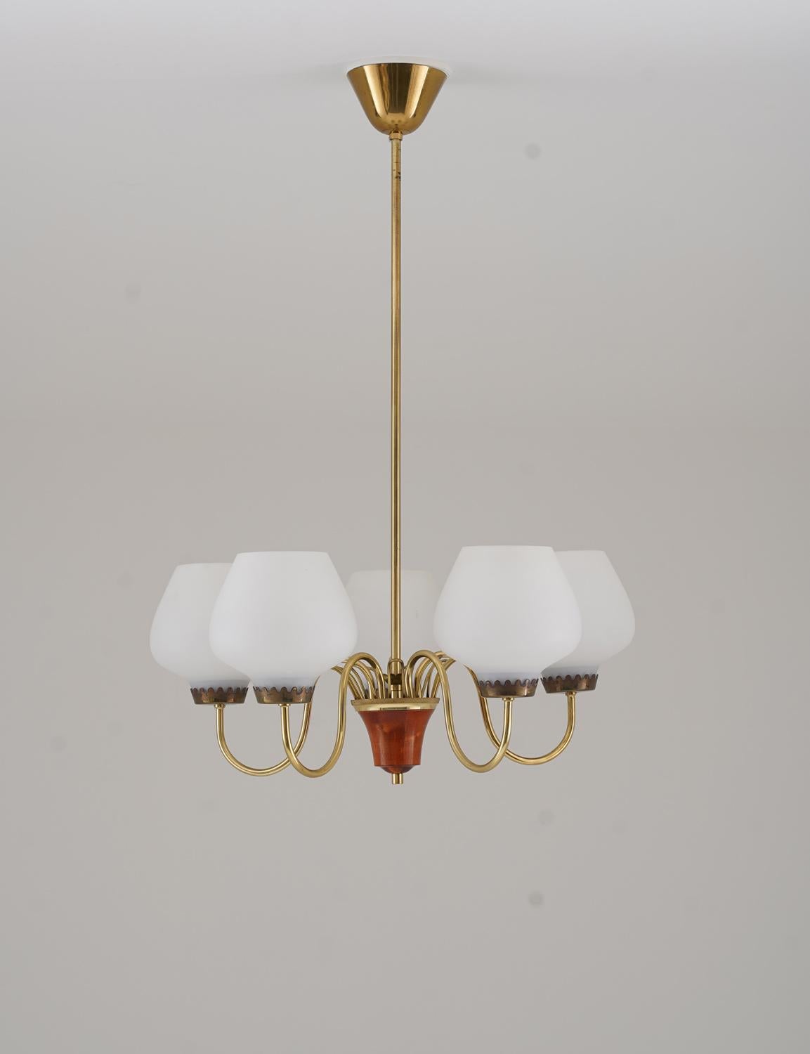 Dieser elegante Kronleuchter aus den 1950er Jahren, hergestellt von ASEA, ist eine raffinierte Mischung aus Messing und Holz. Die anmutig geschwungenen Messingarme gehen von einer zentralen Holznabe aus und tragen Opalglasschirme, die ein weiches,