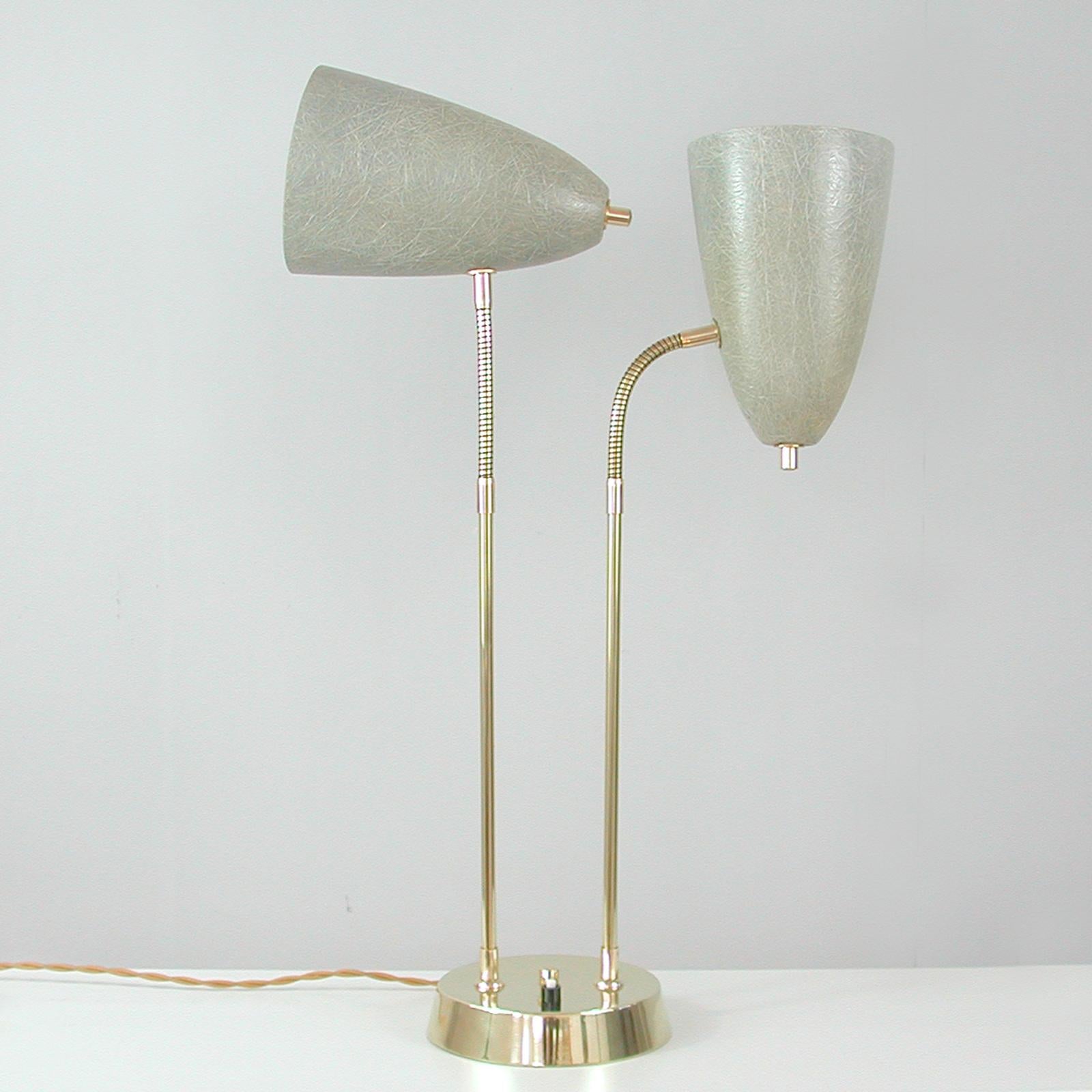 This unusual desk lamp was designed and manufactured in Sweden in the 1950s. It features a brass lamp base, brass lamp rods and two adjustable cone shaped lamp shades made of grey fiberglass. The lamp shades can be turned in any possible direction.