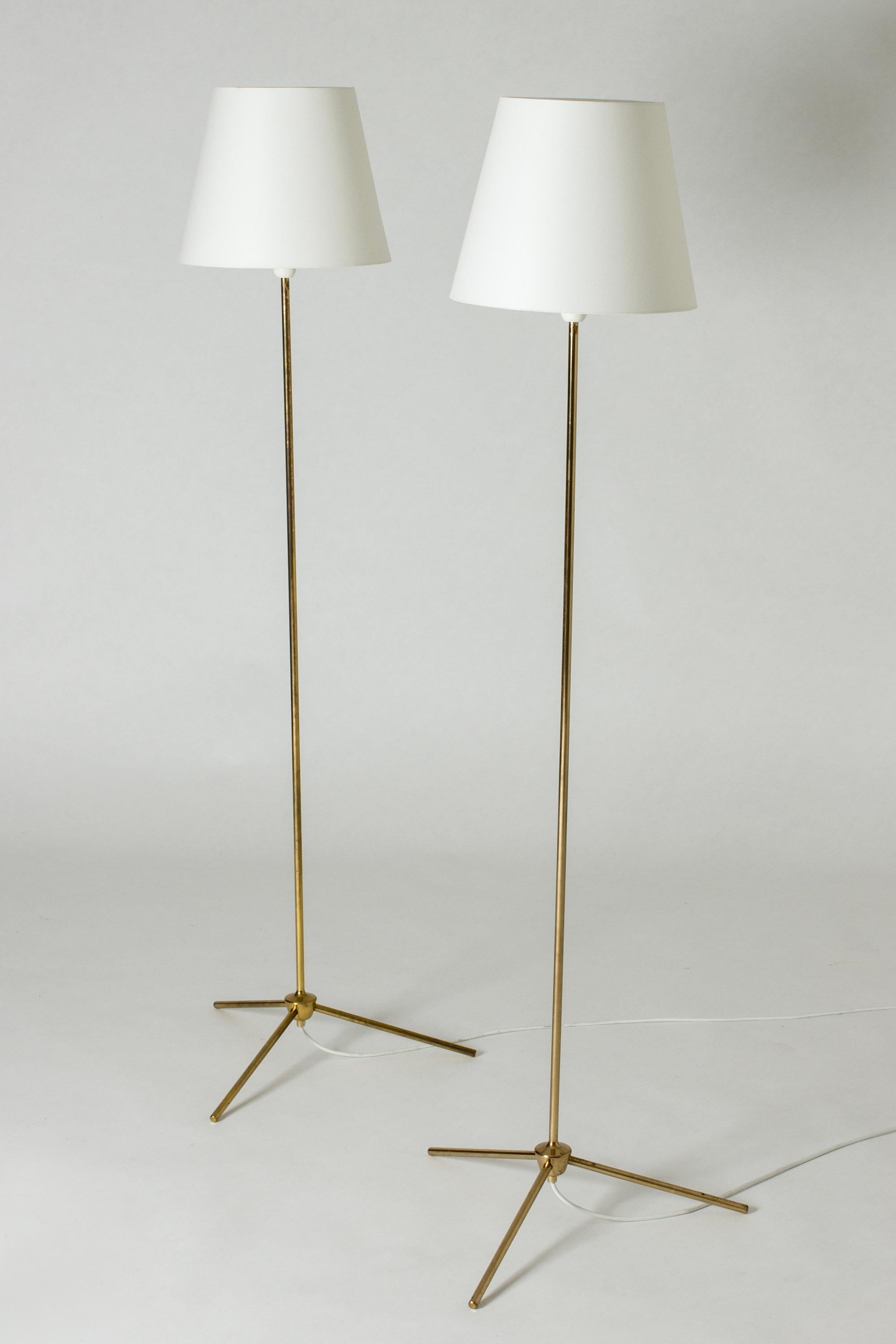 Pair of rare floor lamps from Bergboms. Made with slender brass stems and tripod bases with a chunky decorative detail in the center.