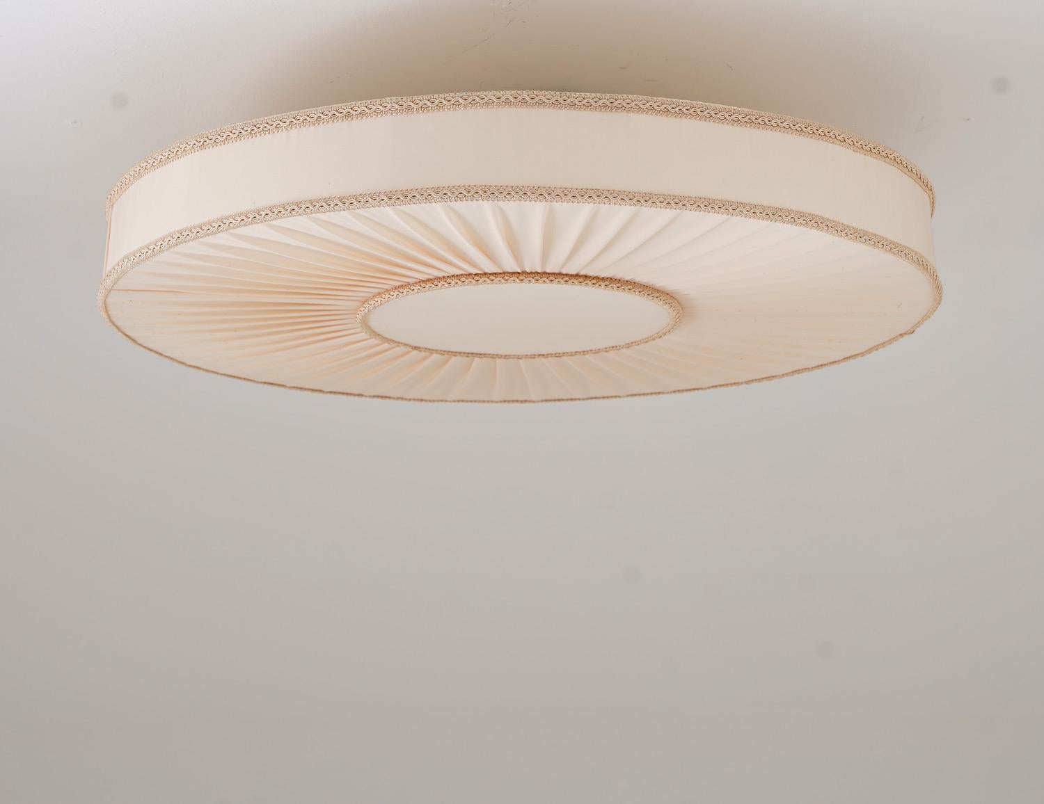 Large flush mount, manufactured in Sweden, 1950s.
The lamp consists of a large round pleated shade, hiding 6 light sources. 

Condition: Good original condition with several minor stains on the shade (which are too small to notice when it's up on