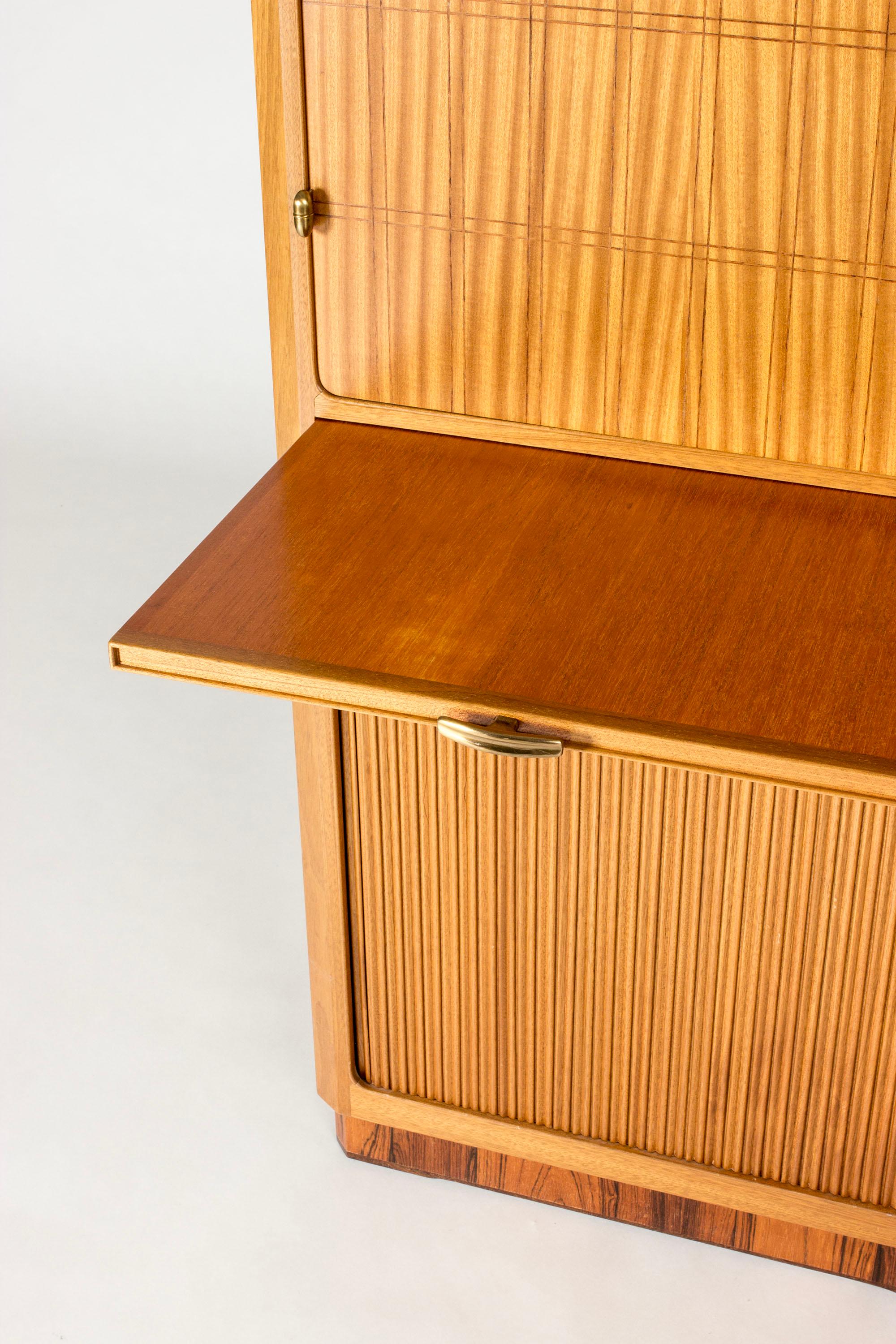Striking cabinet designed by David Rosén and executed by a journeyman as a journeyman’s examination. Boxy, imposing design, offers a lot of storage. Made from mahogany with graphic stripes on the fronts, bottom part with jalousie doors. Brass