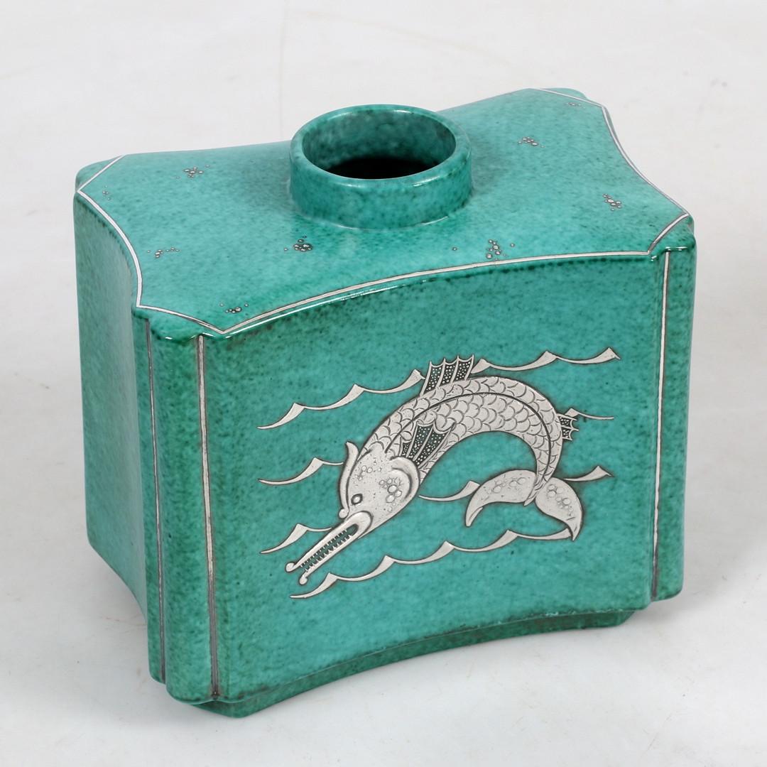 Argenta Vase with mermaid catching a fish on one side and fish on the other side. 

Algot Wilhelm Kåge (6 March 1889 – 25 November 1960) was a Swedish artist and designer, mainly known as a ceramic designer and as the artistic leader of the