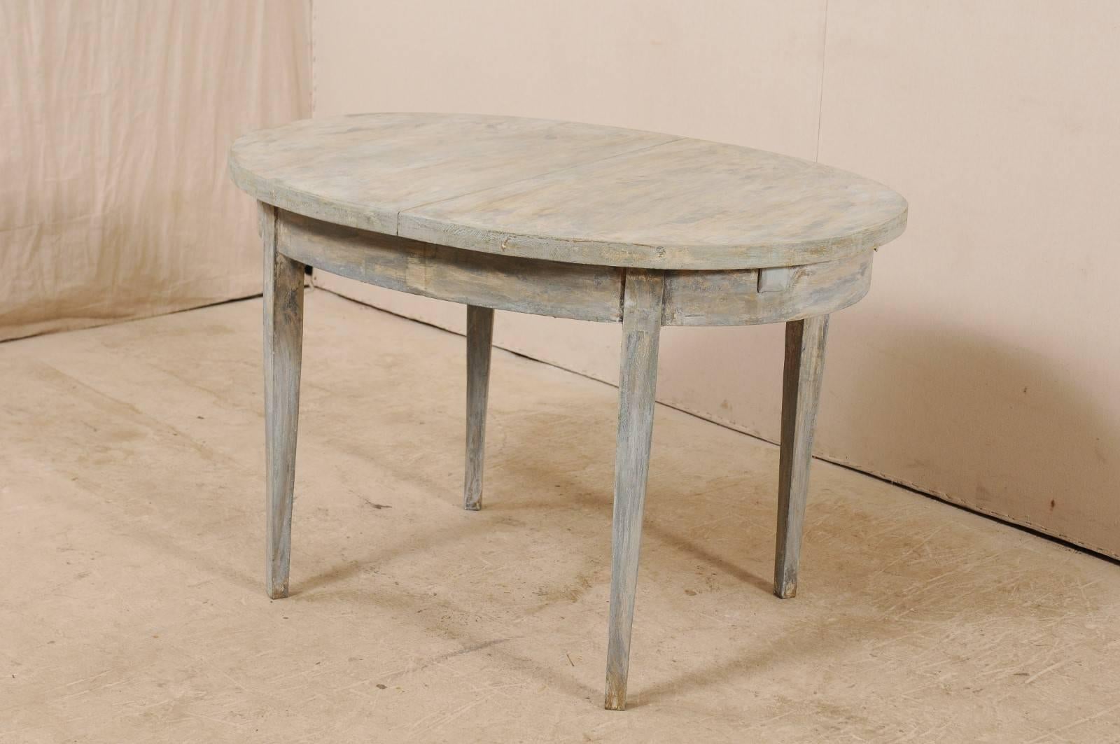 A Swedish midcentury painted wood table. This vintage table from Sweden is designed with simple, clean lines. The table has an oval-shaped top with plain skirt, and is raised upon four gently tapered squared legs. This table has been painted in