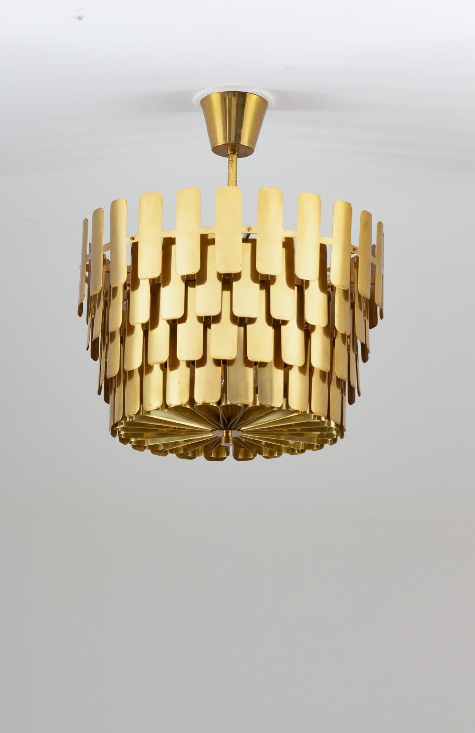 Rare large pendant by Swedish manufacturer Tyringe Konsthantverk.
This impressive lamp is made of brass with a shade constructed by lamellae on different levels. It offers eight light sources hidden by the diffuser that is in the same style as the