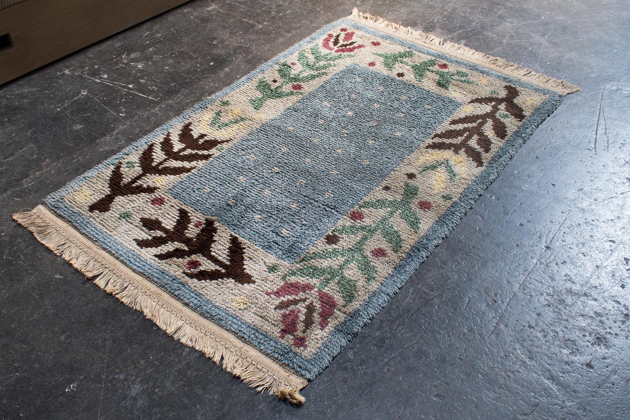 Skandinavisch moderner schwedischer Rya-Teppich. Hellblau, cremefarben, rosa, grün und braun mit floralem Muster. Dieser handgehäkelte Wollteppich eignet sich perfekt für den Nachttisch oder als Überwurf über einen größeren Teppich. Die Farben