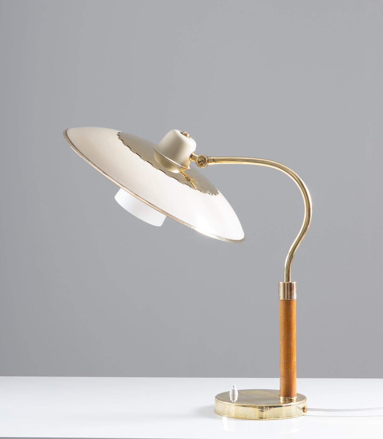 Lampe de table suédoise moderne du milieu du siècle en laiton, verre et bois, produite par Boréns, années 1940.
La lampe se compose d'un grand abat-jour peint en blanc, décoré de détails en laiton poli. L'ampoule est entourée d'un second abat-jour