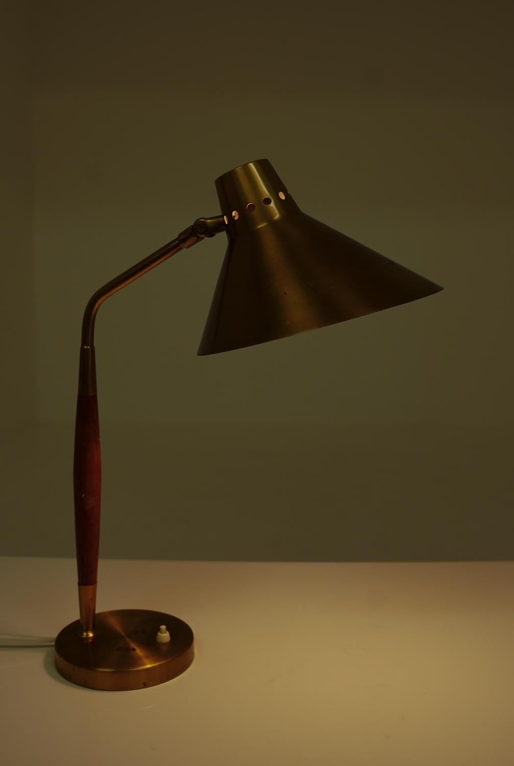 Swedish mid century table lamp model 8458 by Boréns, Sweden.
The design features a slender brass stem with a tapered teak accent, adding warmth and elegance. The conical brass shade is adjustable, allowing for directional lighting, while the sturdy