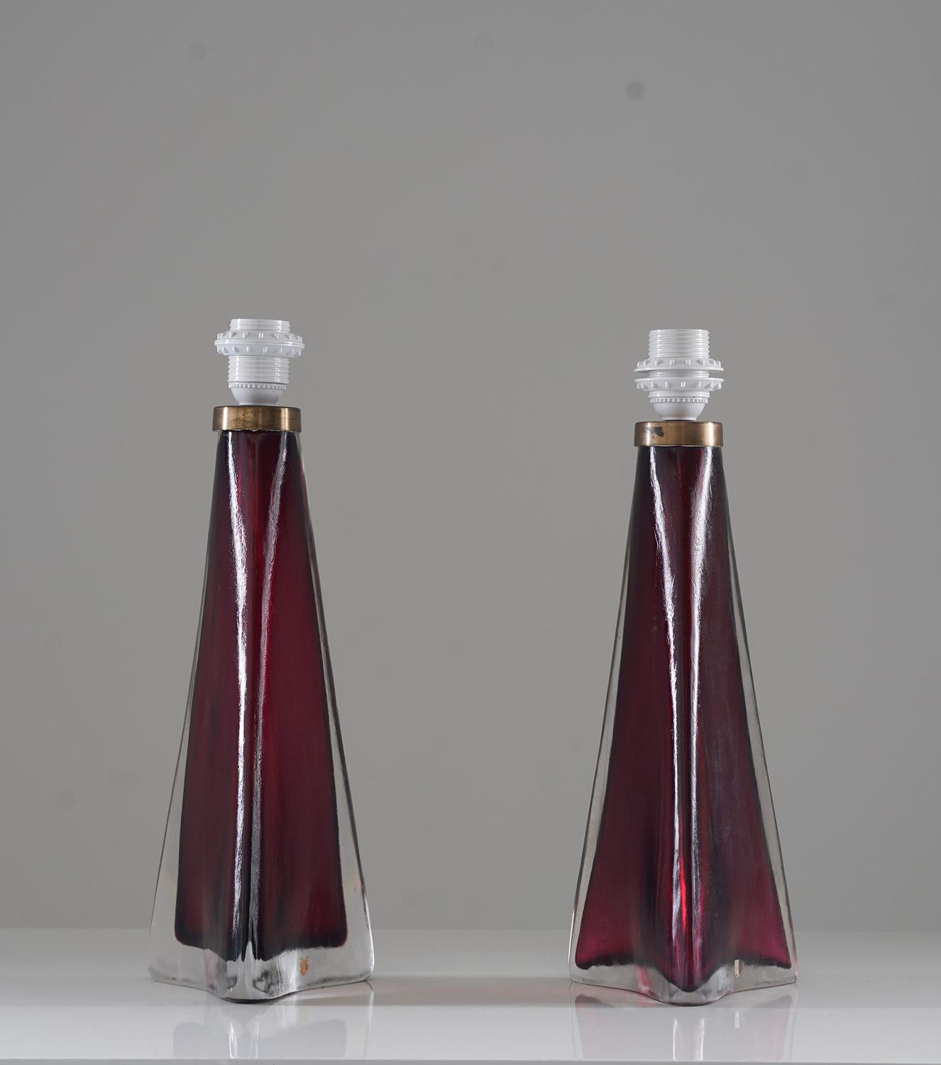 A pair of large table lamps in crystal, model RD1319 by Carl Fagerlund for Orrefors, Sweden. 
The lamps are triangular shaped with stunning wine-red color.
Condition: Very good original condition with signs of age and use on the brass