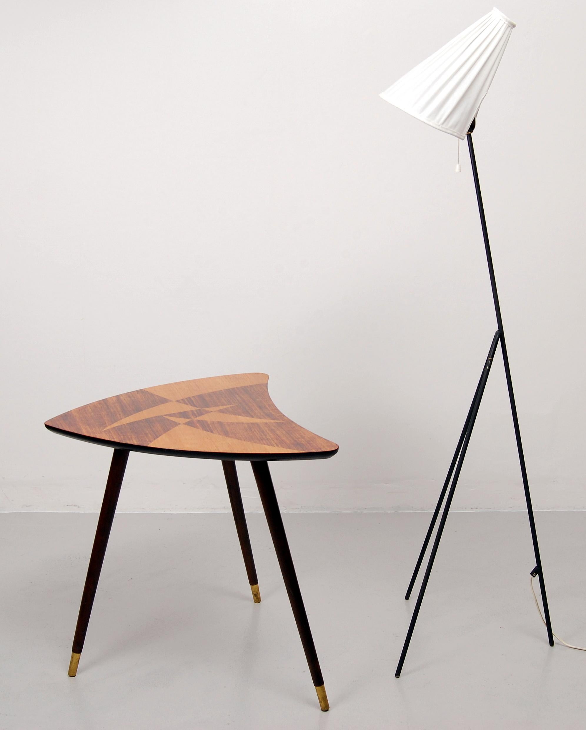 A triangle shaped side table by unknown Swedish manufacturer. The tabletop has two types of veneer. The legs are made of brown stained wood with brass endings.
   