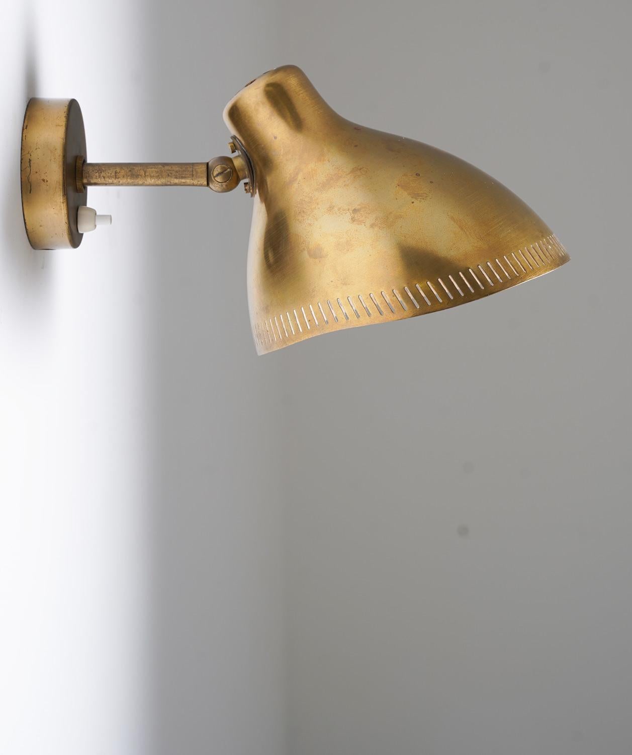 Esta lámpara de pared, diseñada por Hans Bergström para ASEA hacia 1950, personifica el estilo moderno sueco. Fabricada en latón pulido, la pantalla presenta un delicado detalle de borde perforado, que ofrece tanto una iluminación funcional como un