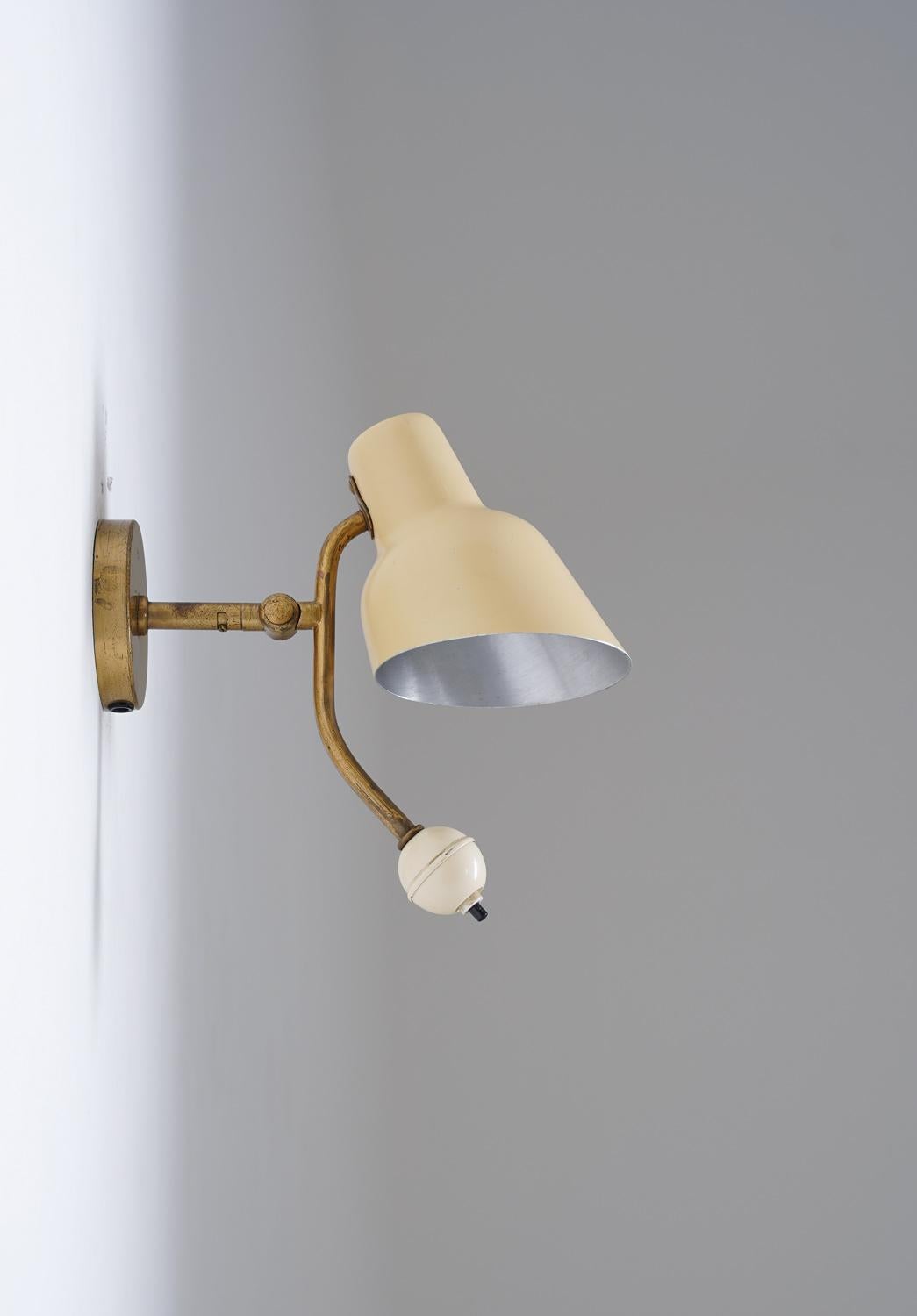 Very rare wall lamp by Bertil Brisborg for Nordiska Kompaniet, 1940s.
This lamp consists of a metal shade, fixtured on an adjustable brass rod. The switch is found at the end of the rod, allowing you to adjust the shade and turn on the light at the