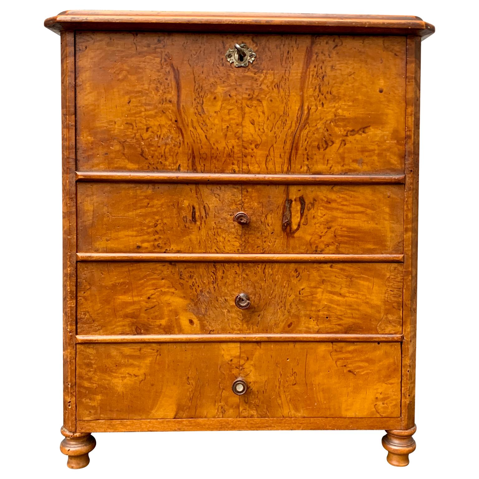 A Swedish 19th Century Biedermeier 3-drawer chest and writing desk with drop down top and a series of small drawers inside. Original antique wooden handles and original locks and 2 keys. 
This miniature in burl birch was most certainly used as a