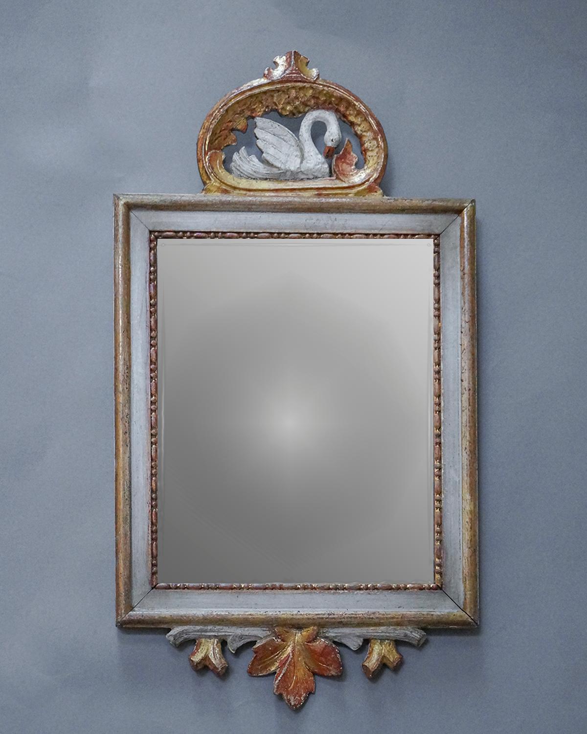 Lovely small wall mirror, Sweden, circa 1860, with a gilded frame. At the top is a carved crest depicting a swan among the waves. At the bottom is a carved leafy branch. Original surface and mirror glass.
