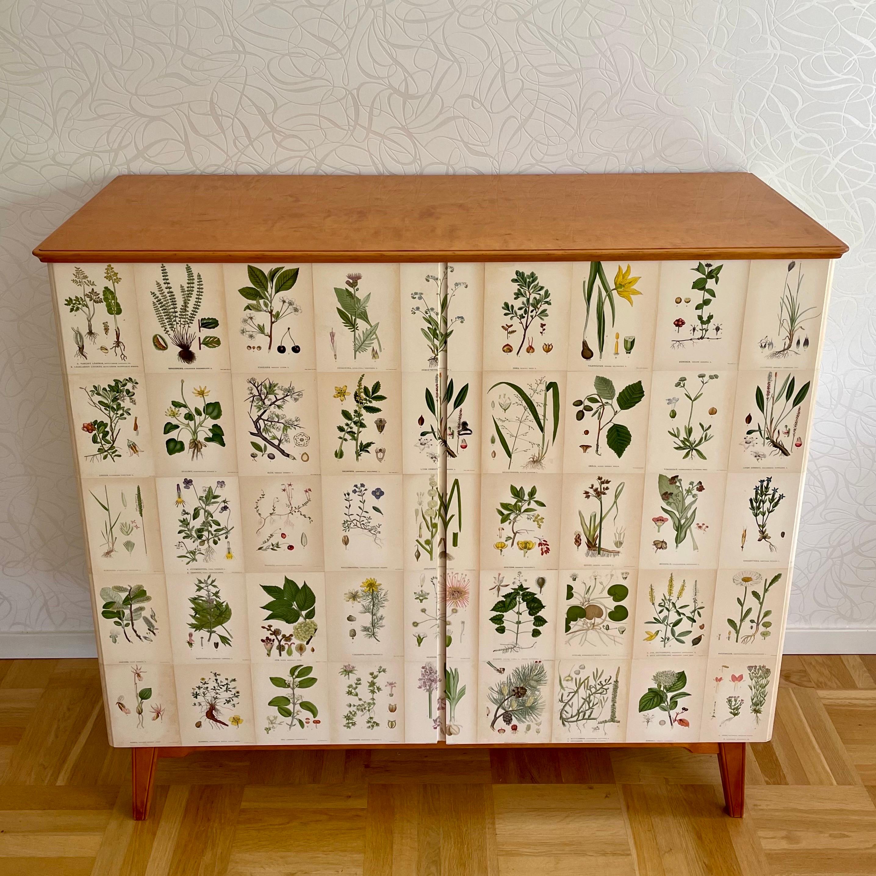 This is a Swedish Modern 1940s birch cabinet decorated with antique floral lithographs in Josef Frank style. 

It comes with clear coat birch veneered top, doors and sides decorated with pages from an antique botanical encyclopedia, 