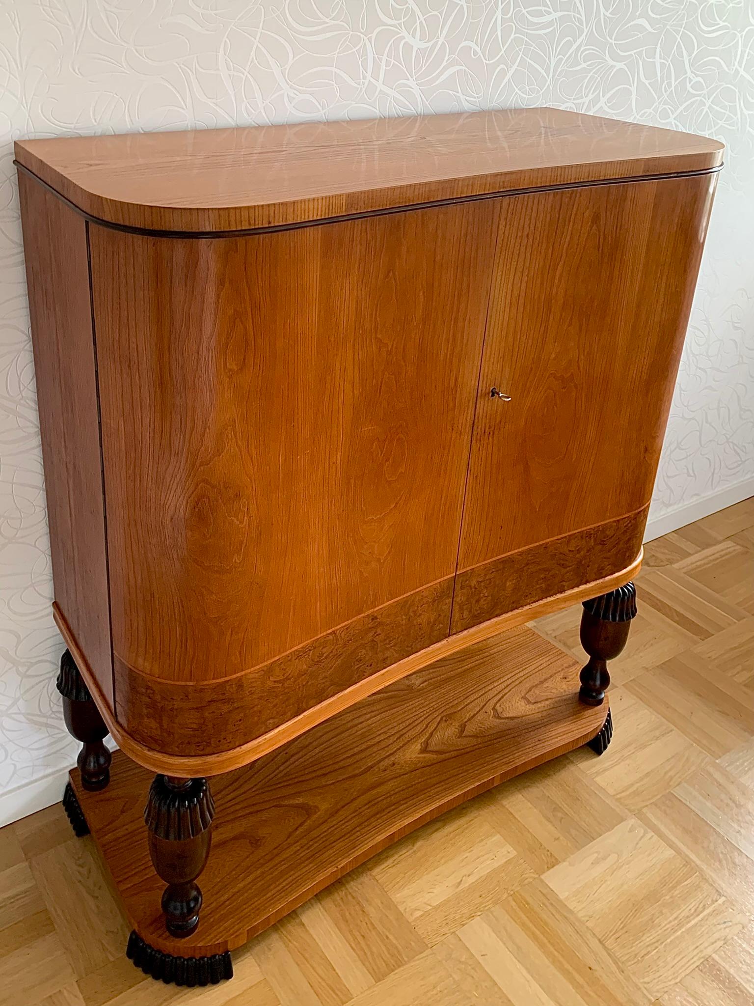 A rare Swedish modern cabinet, with a very special concave form. Made of birch and veneered with elm and elm root. 
 
The top is decorated with a horizontal dark brown stained, softly rounded birch detail. 

Curved doors hide a two-part space