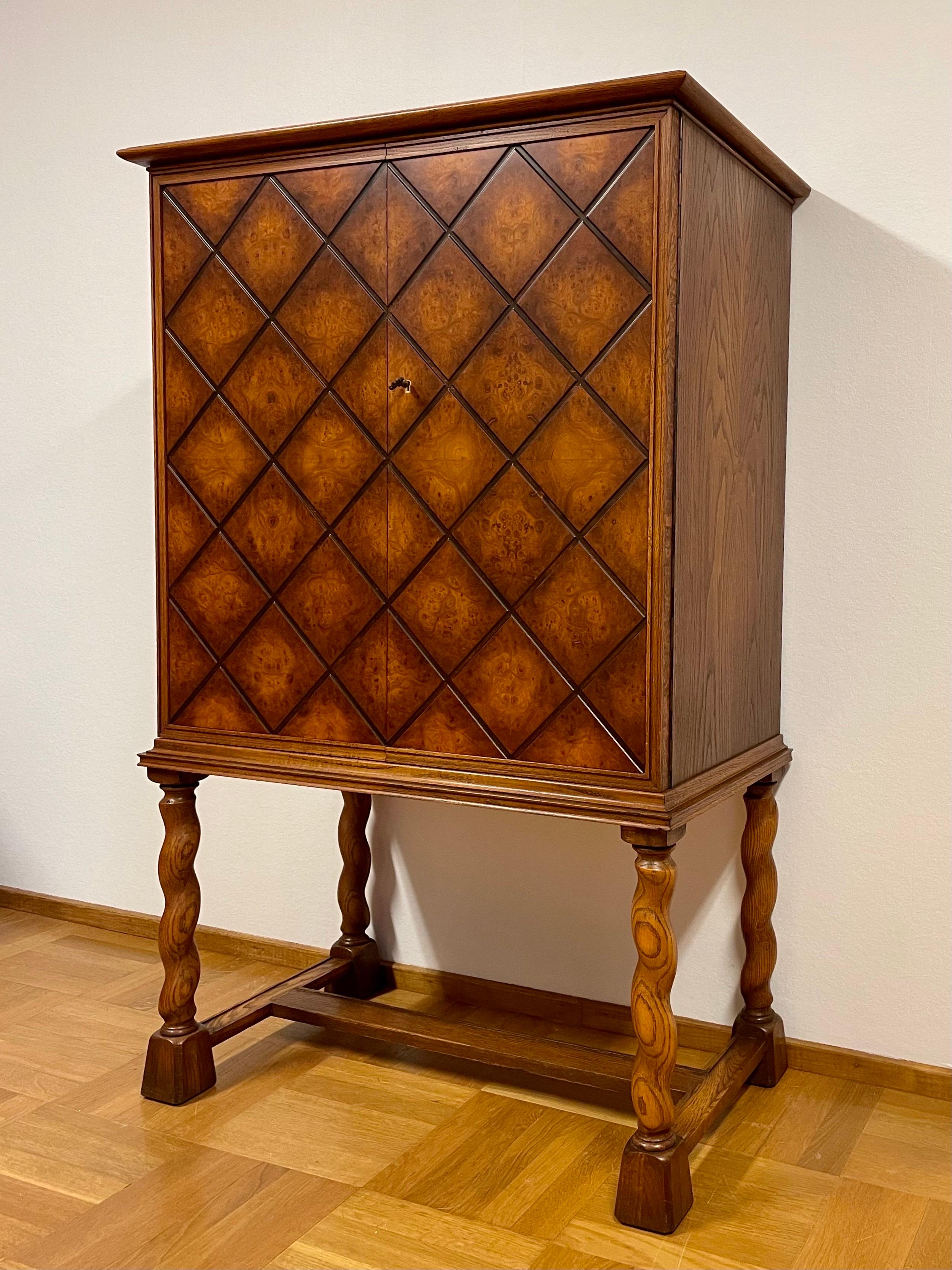 This is the Swedish Modern 1940s cabinet from the furniture factory AB Walfrid Svensson & Co in Karlstad. 

It comes with stained oak burl veneered double doors, decorated with a beautiful geometric grid pattern. The rest of the cabinet, both in-
