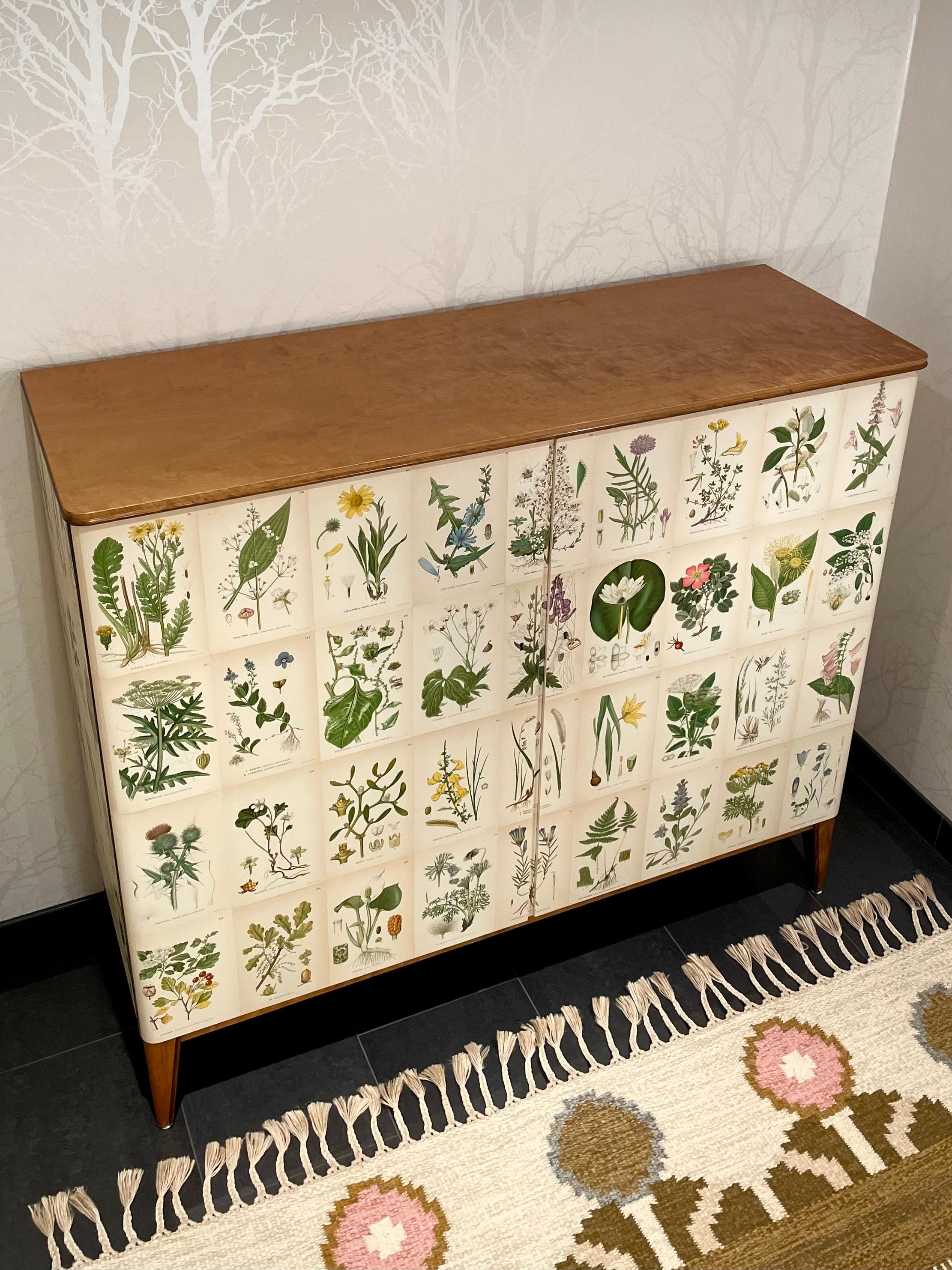 This is the Swedish Modern 1950s cabinet in birch.
It comes decorated with a non-original botanical pattern in the Josef Frank style. The pattern is made of 60 different illustrations from the Swedish antique encyclopedia 