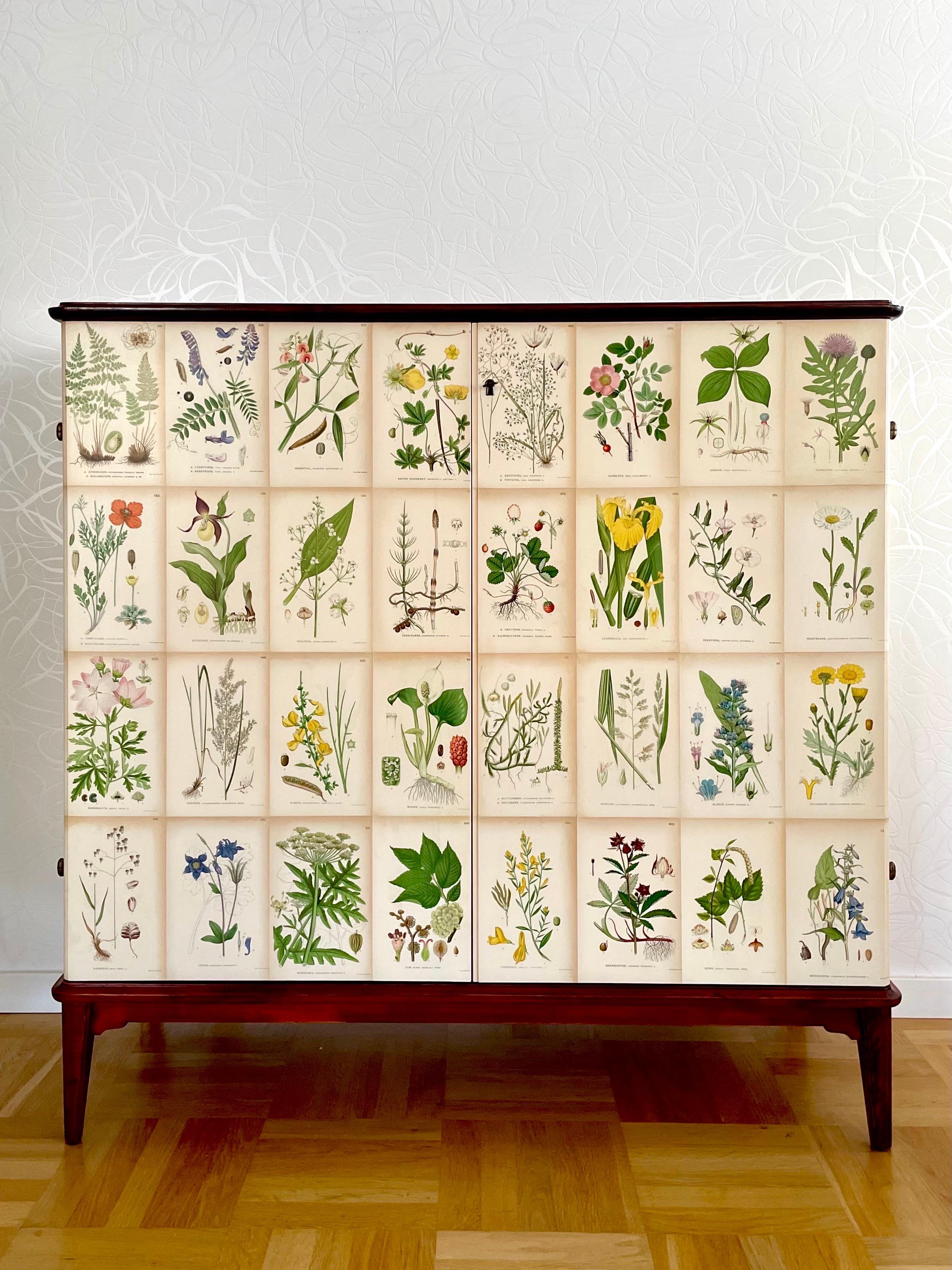 This is a Swedish Modern mahogny cabinet manufactured in 1954, later decorated in Josef Frank style with Nordens Flora lithographs. 

It comes with clear coat mahogany veneered top. There are two doors hiding two drawers and four movable shelves.