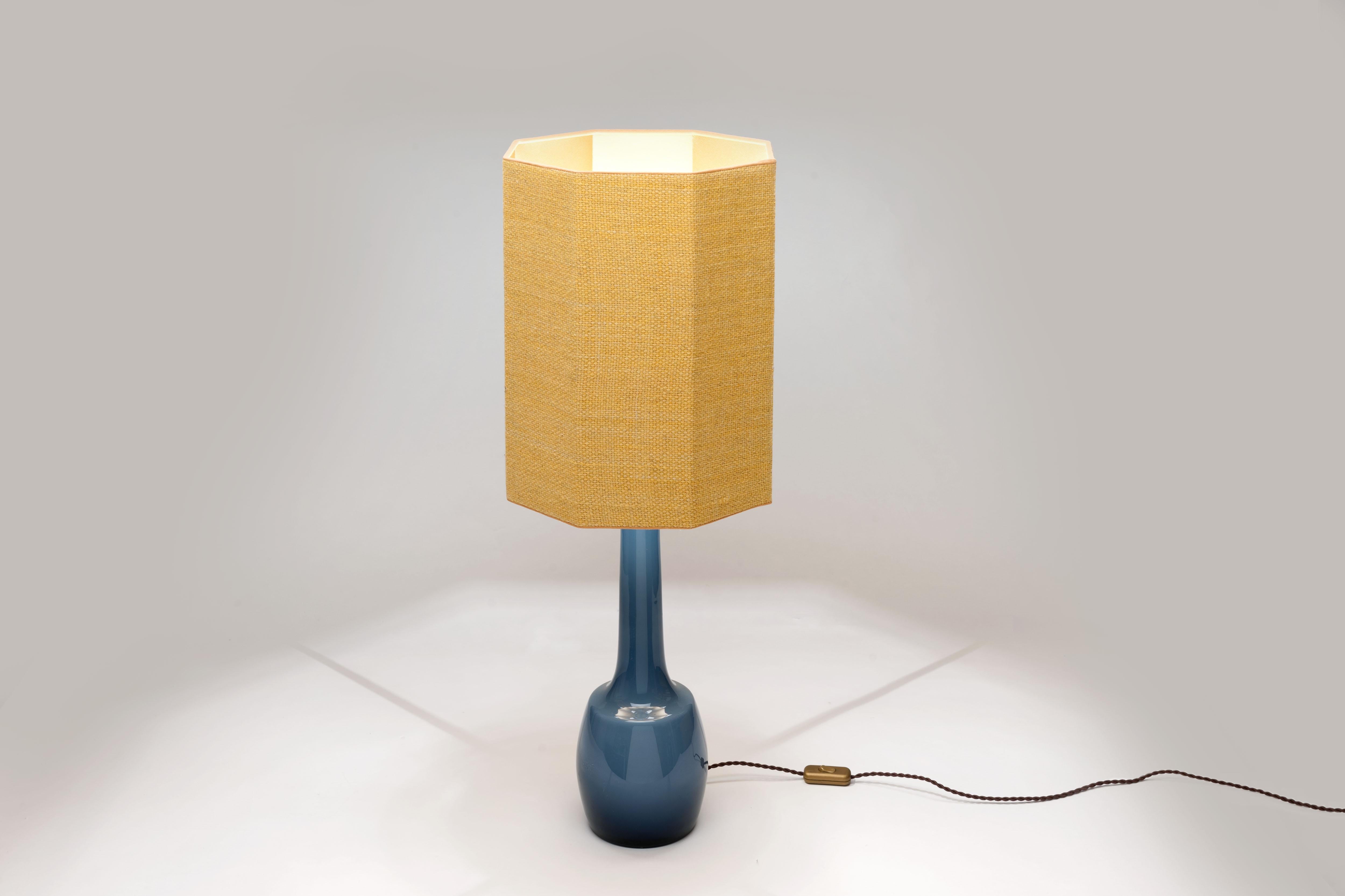 Large blue 1960s glass table lamp by Bergboms, Sweden made by Holmegaard Denmark with brass fittings. The special shade is a high end custom handmade octagonal shaped hood executed in a yellow handwoven coarse linen fabric. The inside of the shade