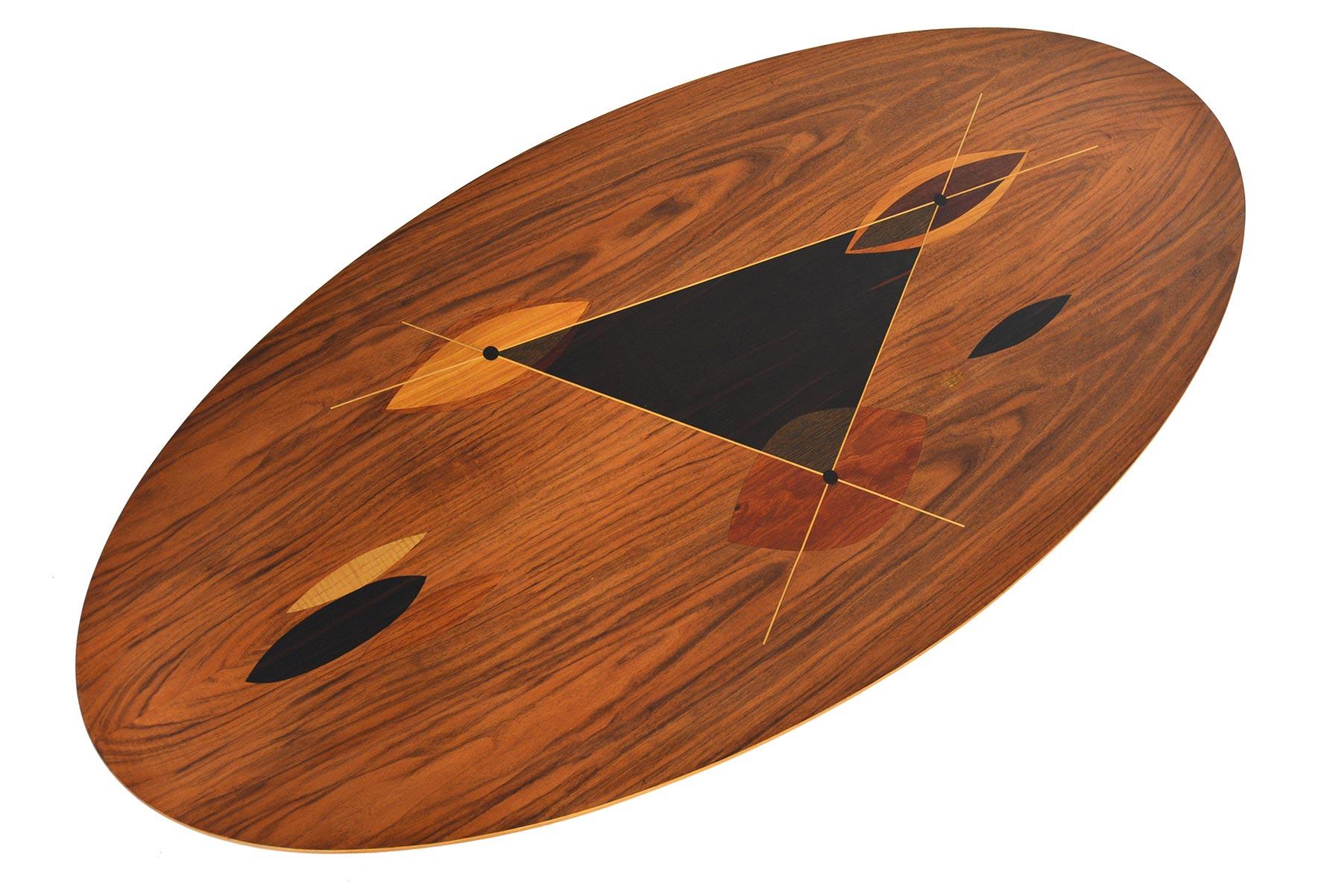 This Swedish modern atomic midcentury coffee table is as stunning close- up as it is from a distance. The beautiful walnut slab features marquetry inlays in oak, mahogany, and rosewood. Table stands on ebonized legs with brass caps. In original