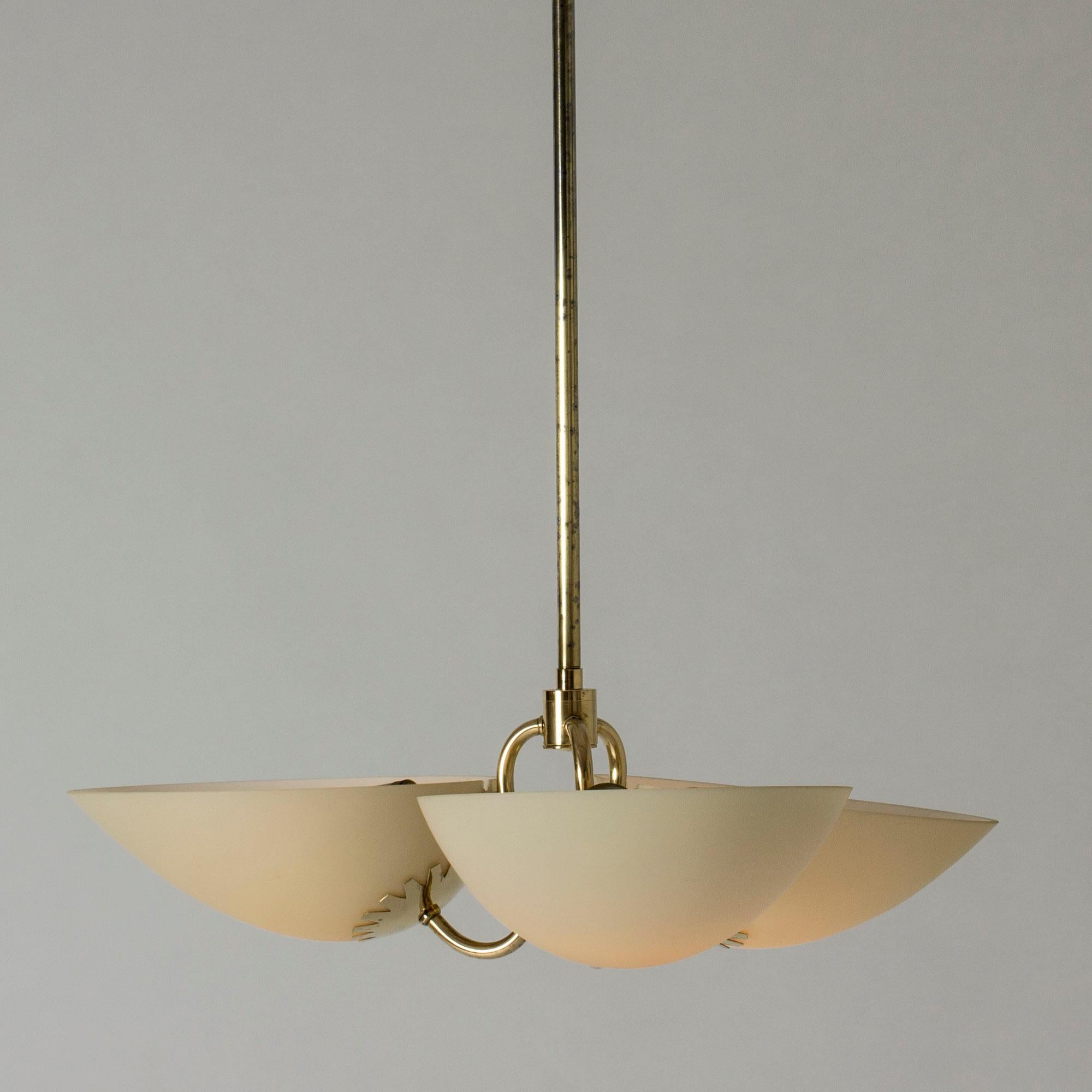 Beautiful brass and glass chandelier from the Swedish Modern period. Clean lines and elegant decorative details. The three shades are made from white, almost opaque glass that have the look of thin marble when lit.