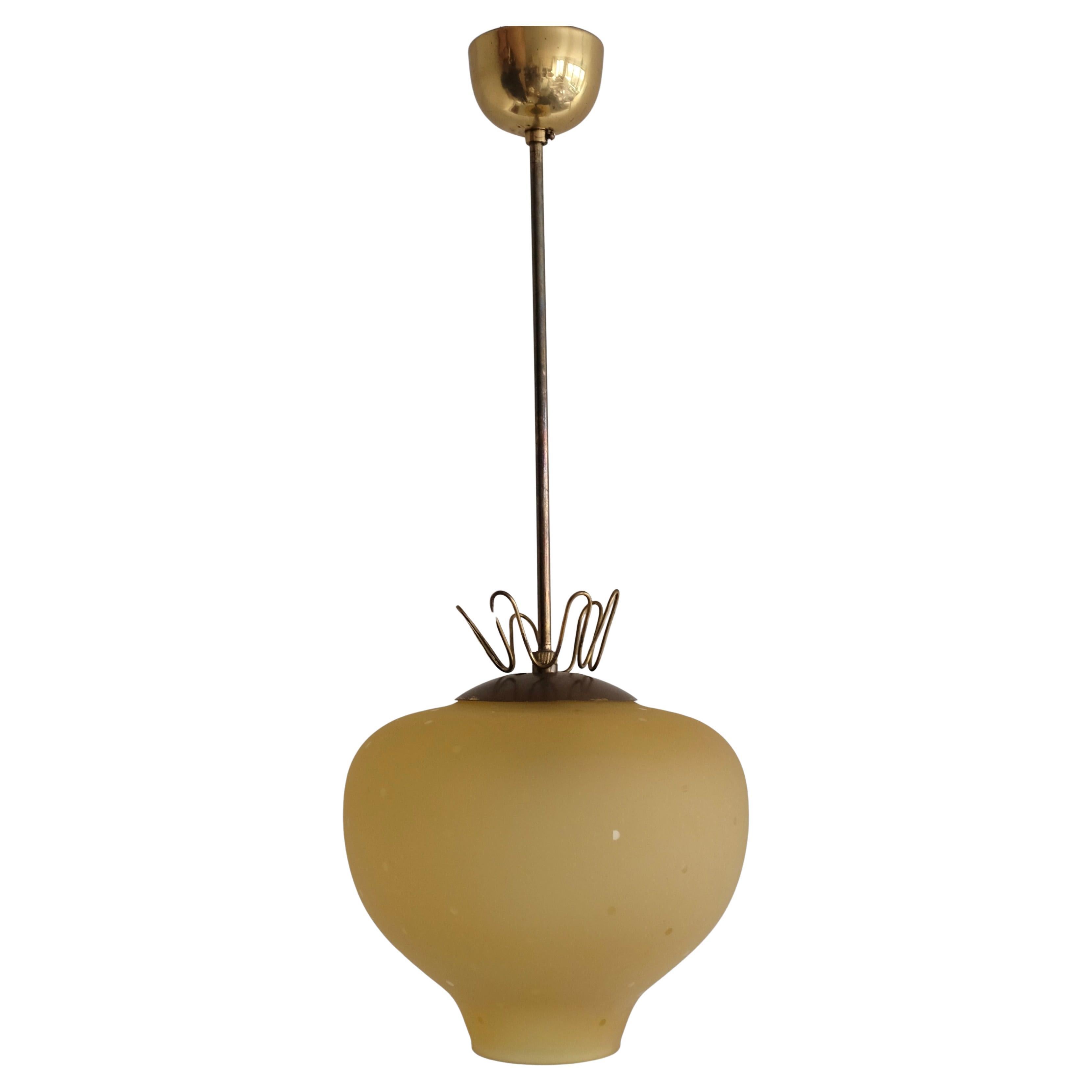 Lovely Brass and Yellow frosted Glass Pendant from Sweden circa 1940/50s. The glass pendant has a decorative oval shape with small dots in the frosted glass surface. On top of the pendant sits a wavy filigree brass detail that adds charm to the