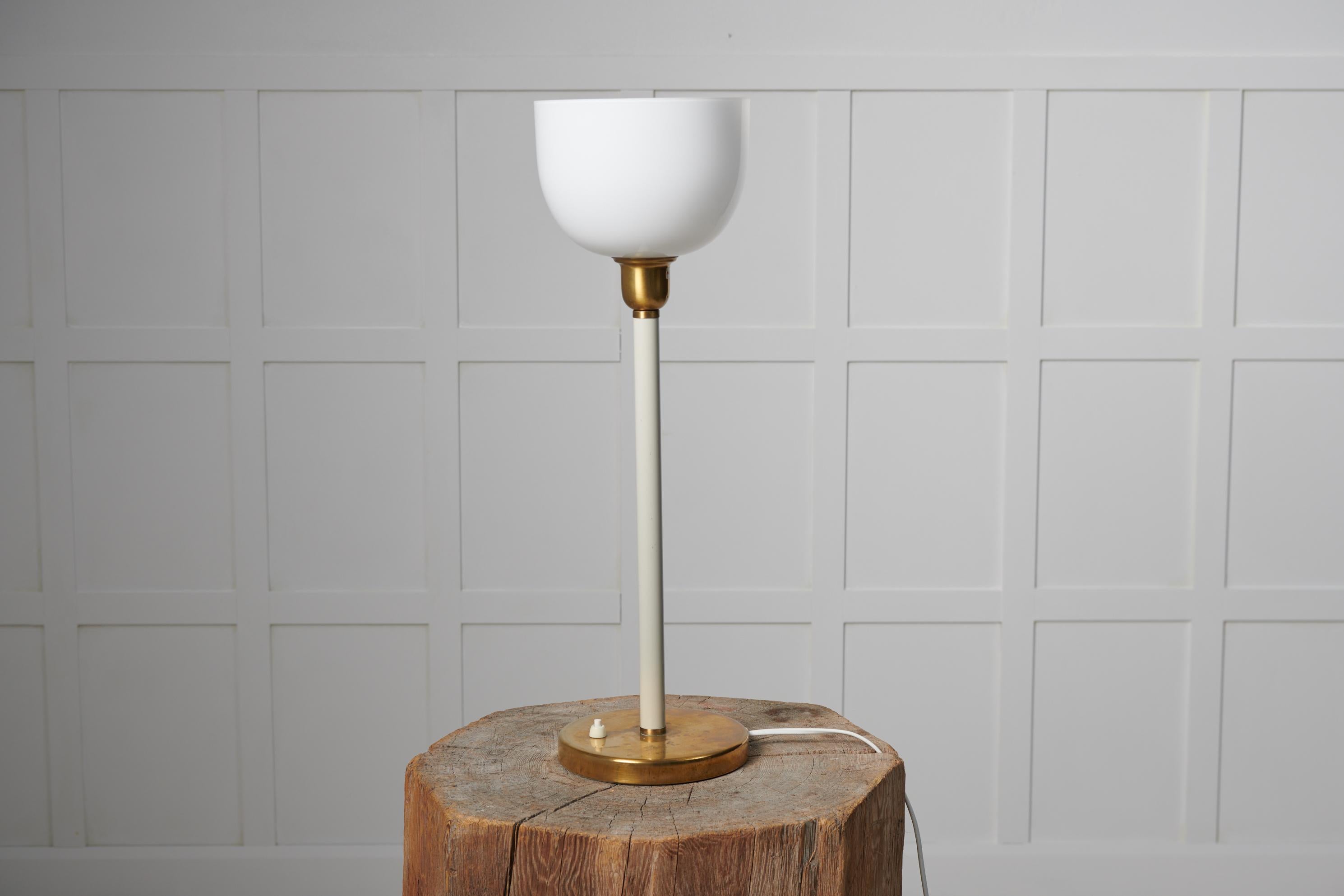 Swedish modern table light from the 1930s to 1940s. The light is likely by Böhlmarks. It has a foot in brass and a white stem. The shade to the light is original and made in white opaline glass. The electrics are new and made according to the EU